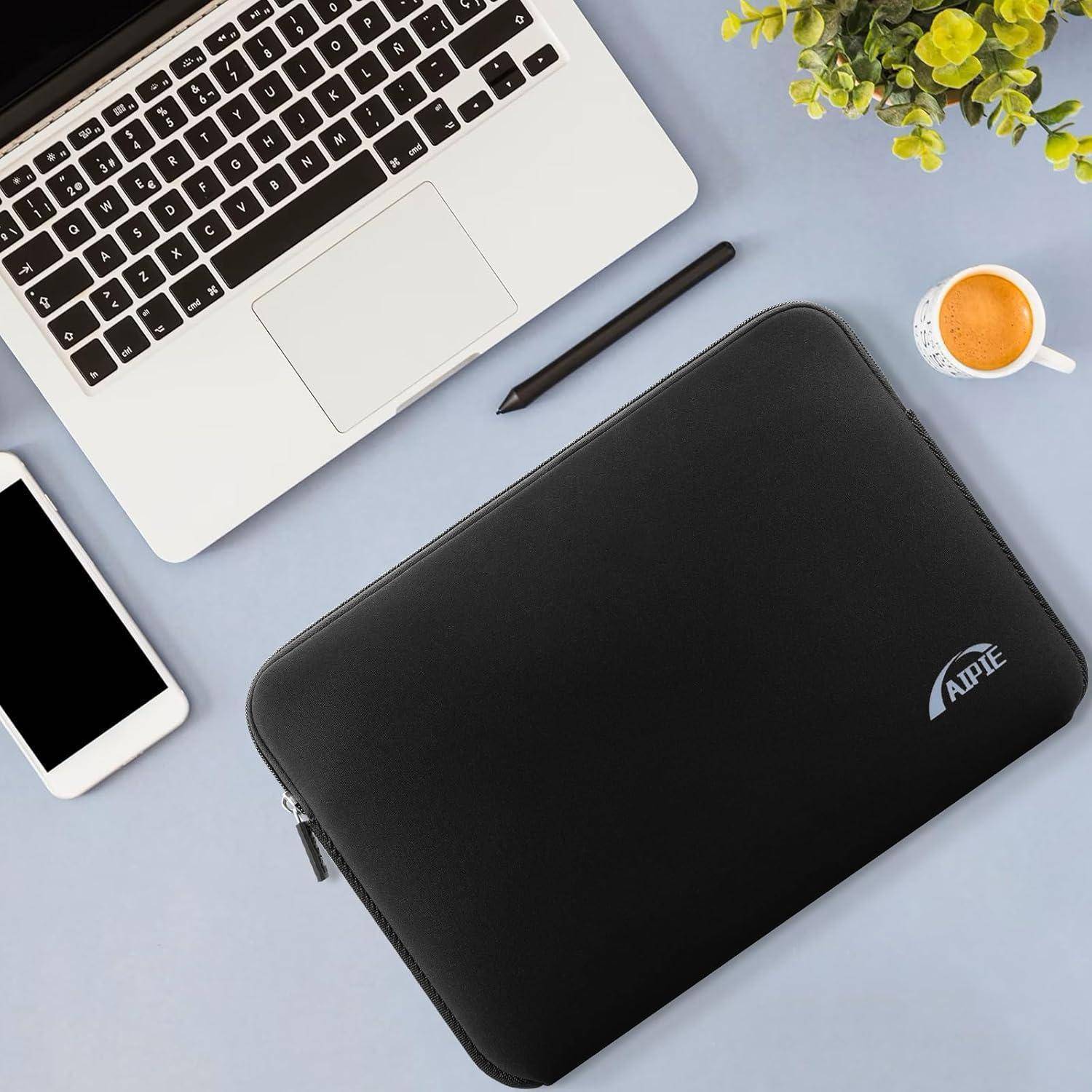 Ein Laptop, ein Smartphone, ein Stift, ein Notizbuch und eine Kaffeetasse sind auf einem hellblauen Schreibtisch neben einer kleinen Pflanze angeordnet.