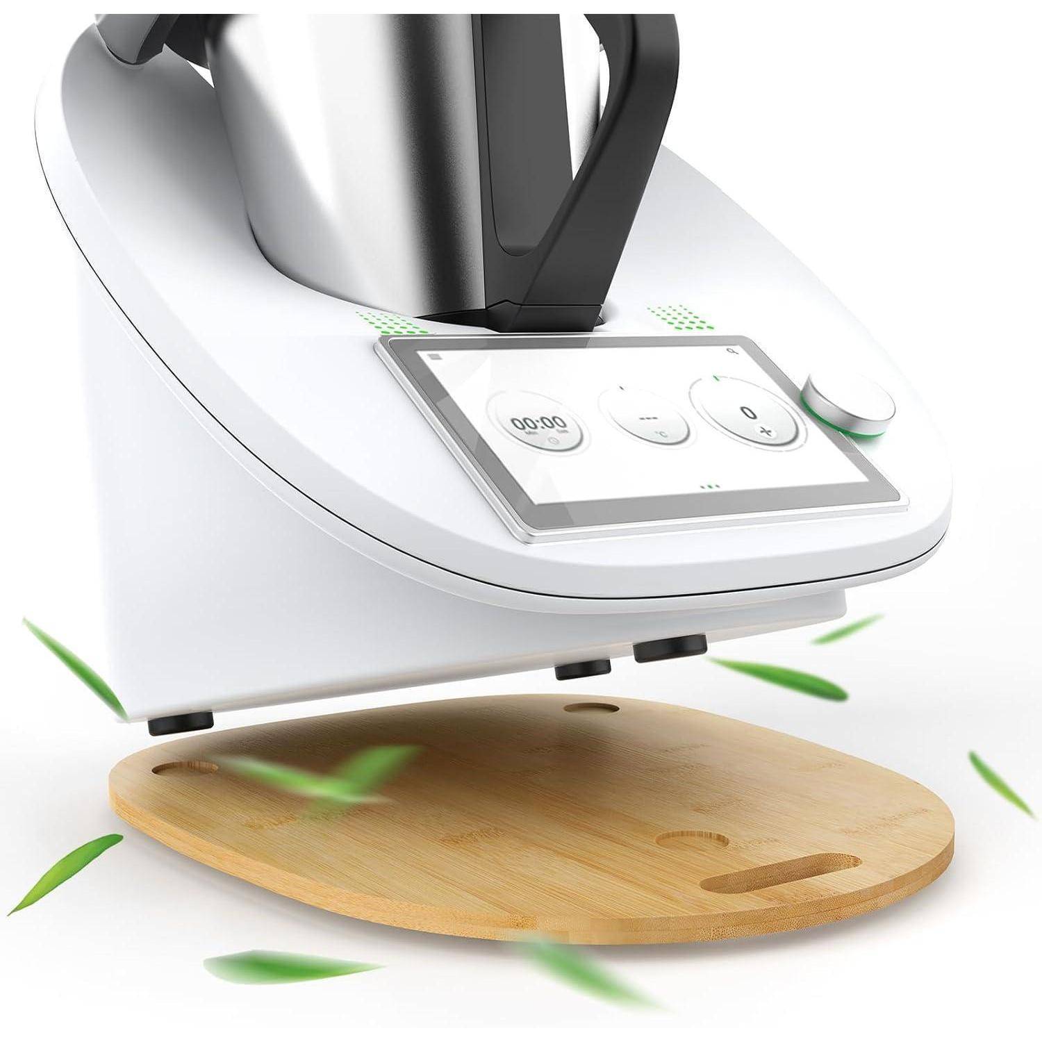 Weißes Küchengerät mit digitalem Bildschirm, auf einem Holzbrett platziert. Grüne Blätter verstreut, was Frische oder Kochen andeutet.