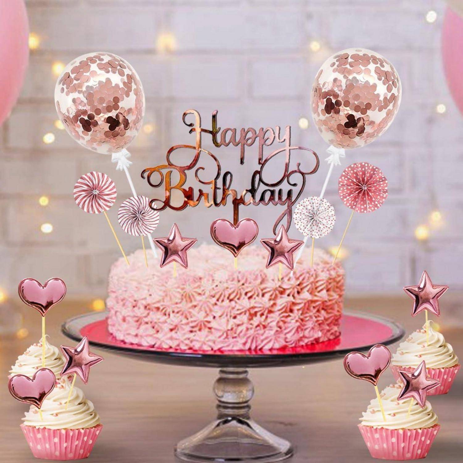 Pink-Geburtsfeier mit einer dekorierten Torte auf einem Ständer und Cupcakes, mit Luftballons und einem 