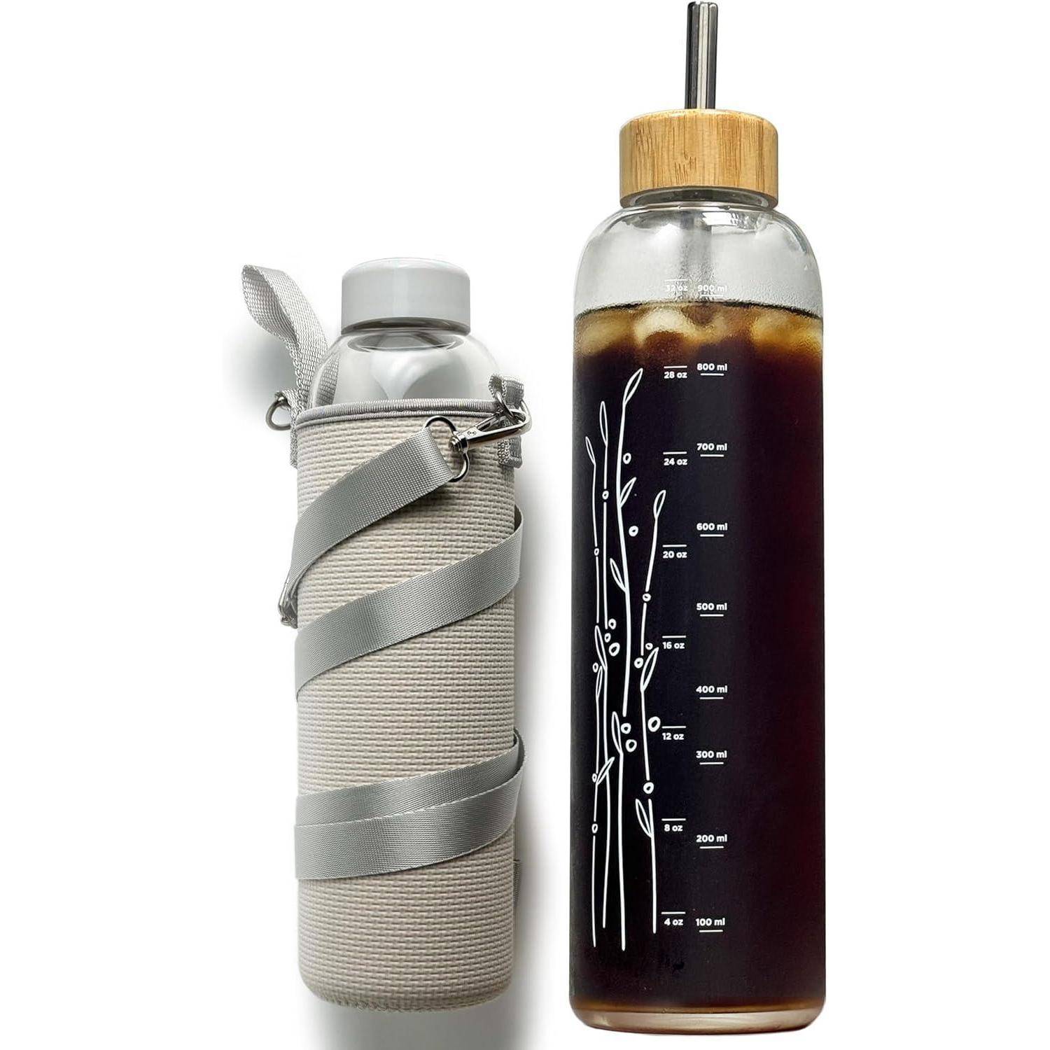 Zwei Glasflaschen: eine mit einem grauen Stoffüberzug und einem Trageriemen versehen und die andere mit einem Bambusdeckel, gefüllt mit Eiskaffee und sichtbaren Volumenmarkierungen.