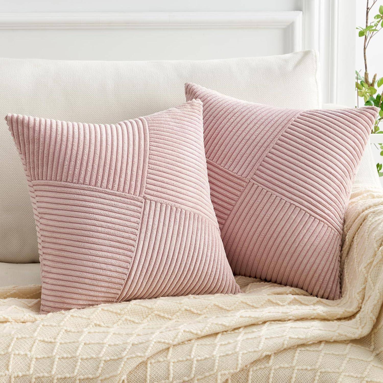 Zwei rosa, strukturierte Kissen auf einem cremefarbenen Sofa mit einer beigen Decke, die eine gemütliche und einladende Atmosphäre schaffen.