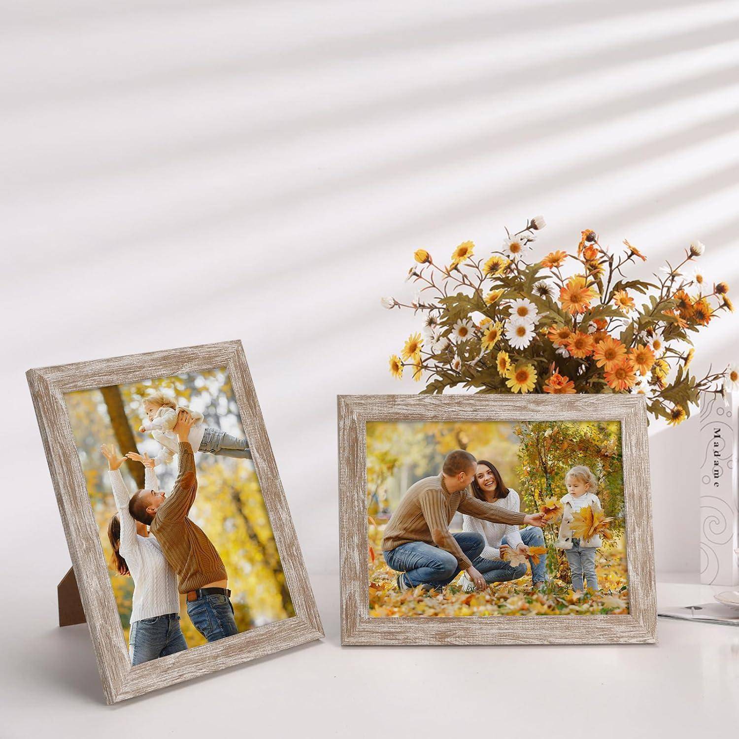 Zwei gerahmte Fotos auf einem Regal: ein Vater, der ein Kind vor herbstlichem Laubwerk hochhebt, und eine Familie, die in Herbstblättern spielt. Eine Vase mit Blumen steht daneben.