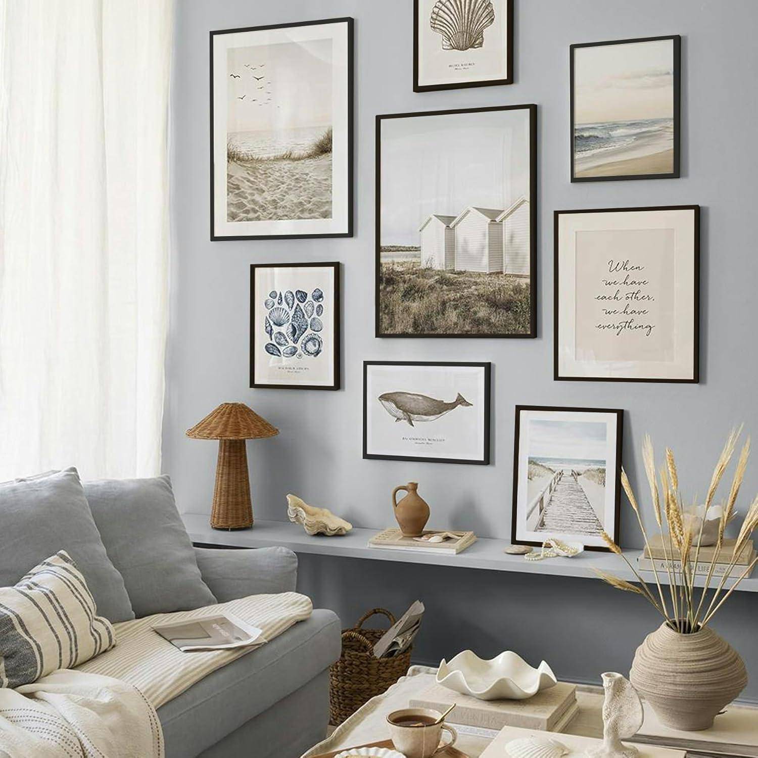 Wohnzimmer mit einem grauen Sofa, dekorativen Kissen, einem Holztisch und einer Wandcollage mit naturthematischen Kunstdrucken in schwarzen Rahmen.