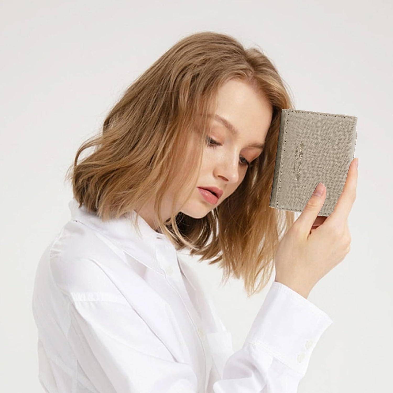 Eine Person mit schulterlangem Haar in einem weißen Hemd hält eine beige Geldbörse nah an ihrem Gesicht und blickt nachdenklich nach unten.