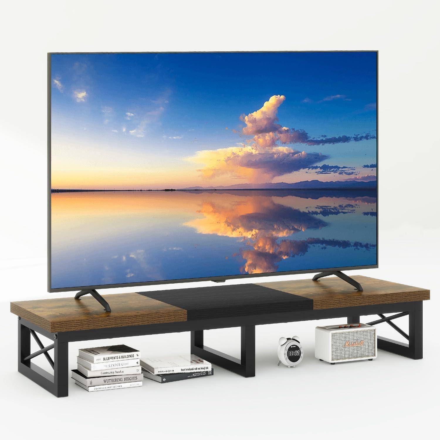 Ein großer Flachbildschirm-Fernseher zeigt einen friedlichen Sonnenuntergang über einem ruhigen Gewässer. Er steht auf einem stilvollen Ständer aus Holz und Metall, auf dem Bücher und ein Lautsprecher platziert sind.