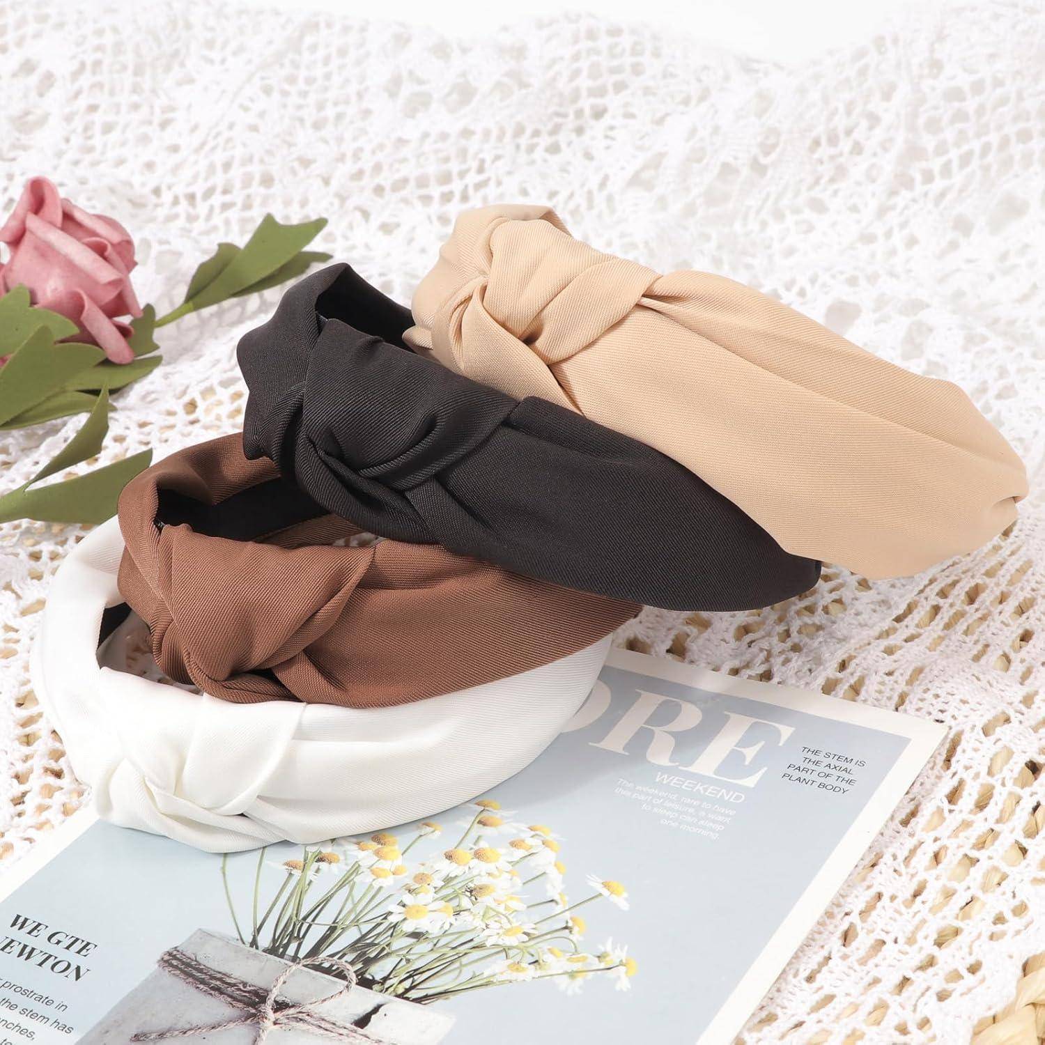 Vier geknotete Haarreifen in Schwarz, Beige, Braun und Weiß auf einem Spitzentuch neben einer Zeitschrift und einer rosa Rose.