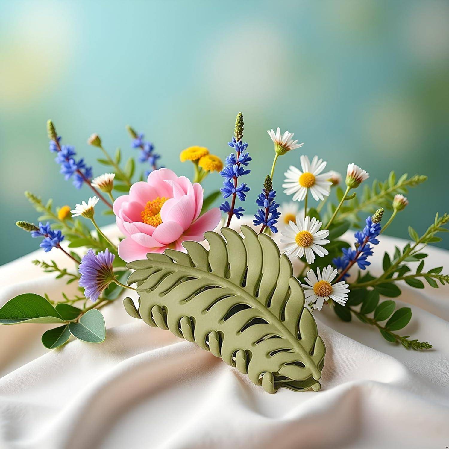 Eine lebendige Blumenkomposition mit rosa, blauen und weißen Blüten und einem großen grünen Blatt als Mittelpunkt, vor einem sanften Hintergrund.