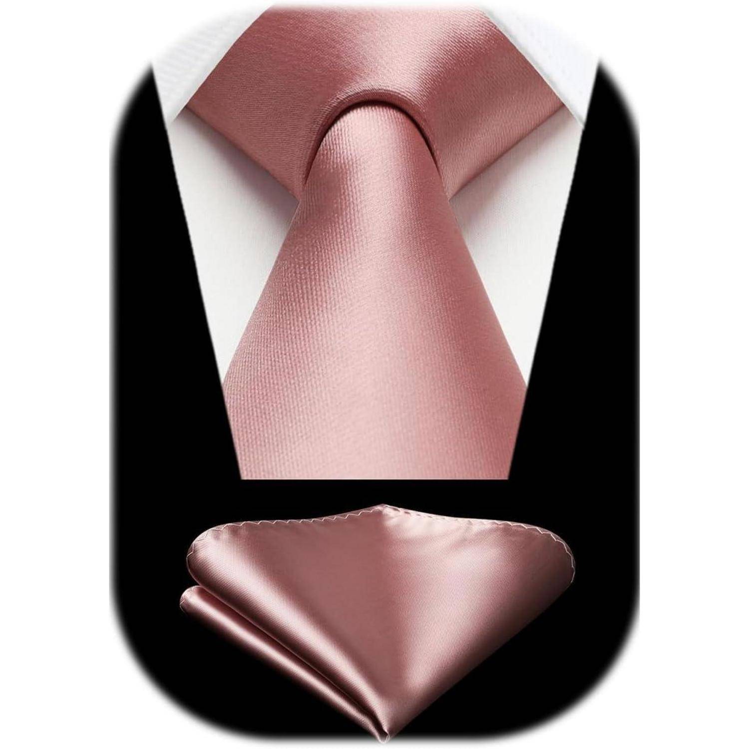 Eine rosa Seidenhalsbinde und ein passendes Einstecktuch vor schwarzem Hintergrund, mit einem weißen Hemdkragen, der die Krawatte umrahmt.