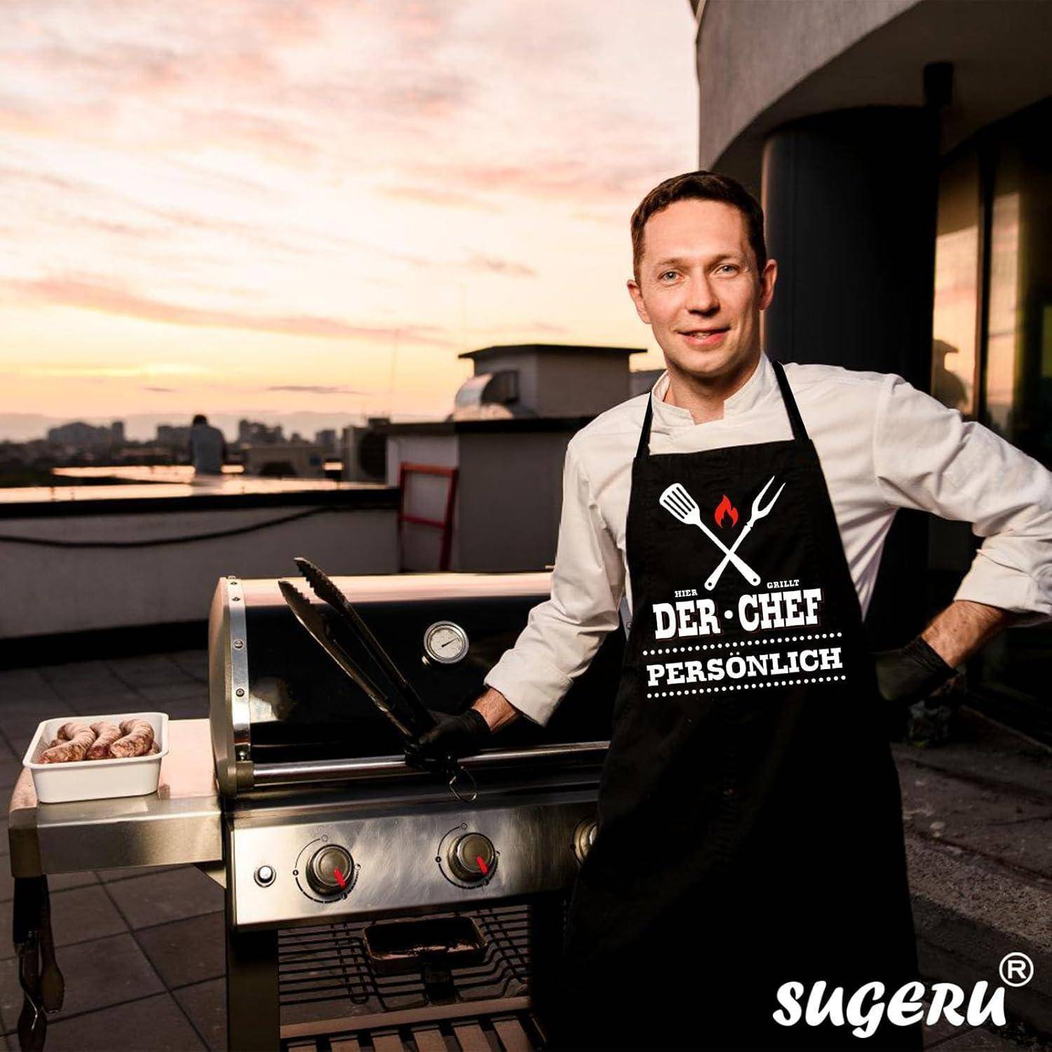 Eine Person steht neben einem Grillgerät auf einem Dachgarten bei Sonnenuntergang und trägt eine Schürze mit der Aufschrift 