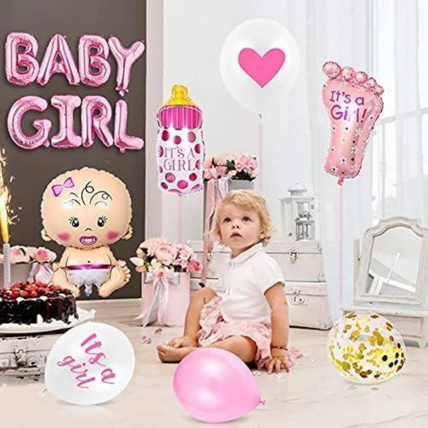 Ein Kleinkind sitzt auf dem Boden, umgeben von rosa und weißen Luftballons, einer Torte und Dekorationen mit den Aufschriften „BABY MÄDCHEN