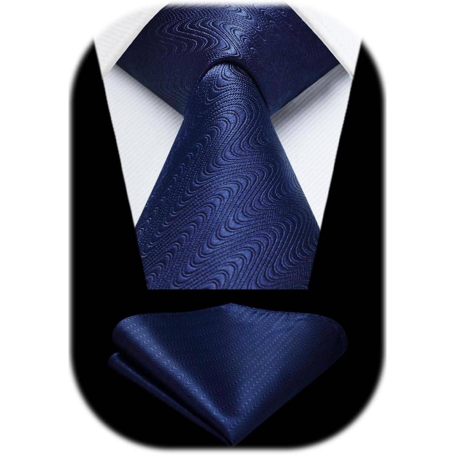 Eine marineblau-farbene Krawatte und ein passendes Einstecktuch mit einem dezenten Wellenmuster, präsentiert vor einem weißen Hemd.