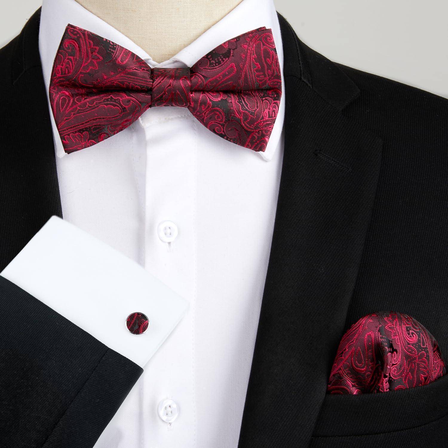 Eine Person in einem schwarzen Smoking mit weißem Hemd, die eine rote Paisley-Fliege und ein passendes Einstecktuch trägt und damit formelle Kleidungsdetails präsentiert.