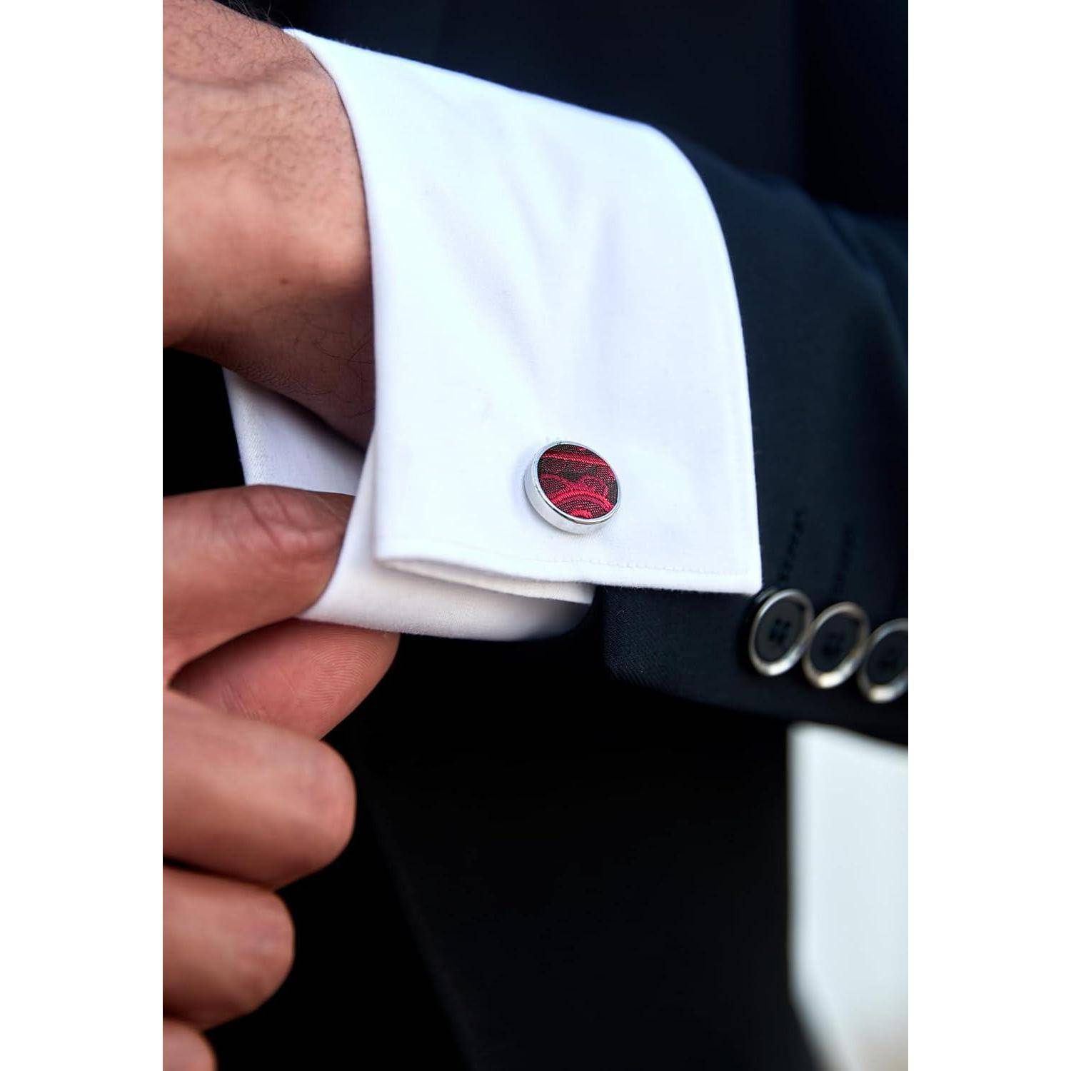 Eine Person richtet die Manschette eines schwarzen Blazers, wobei ein weißes Hemd mit einem roten Manschettenknopf zur Geltung kommt.