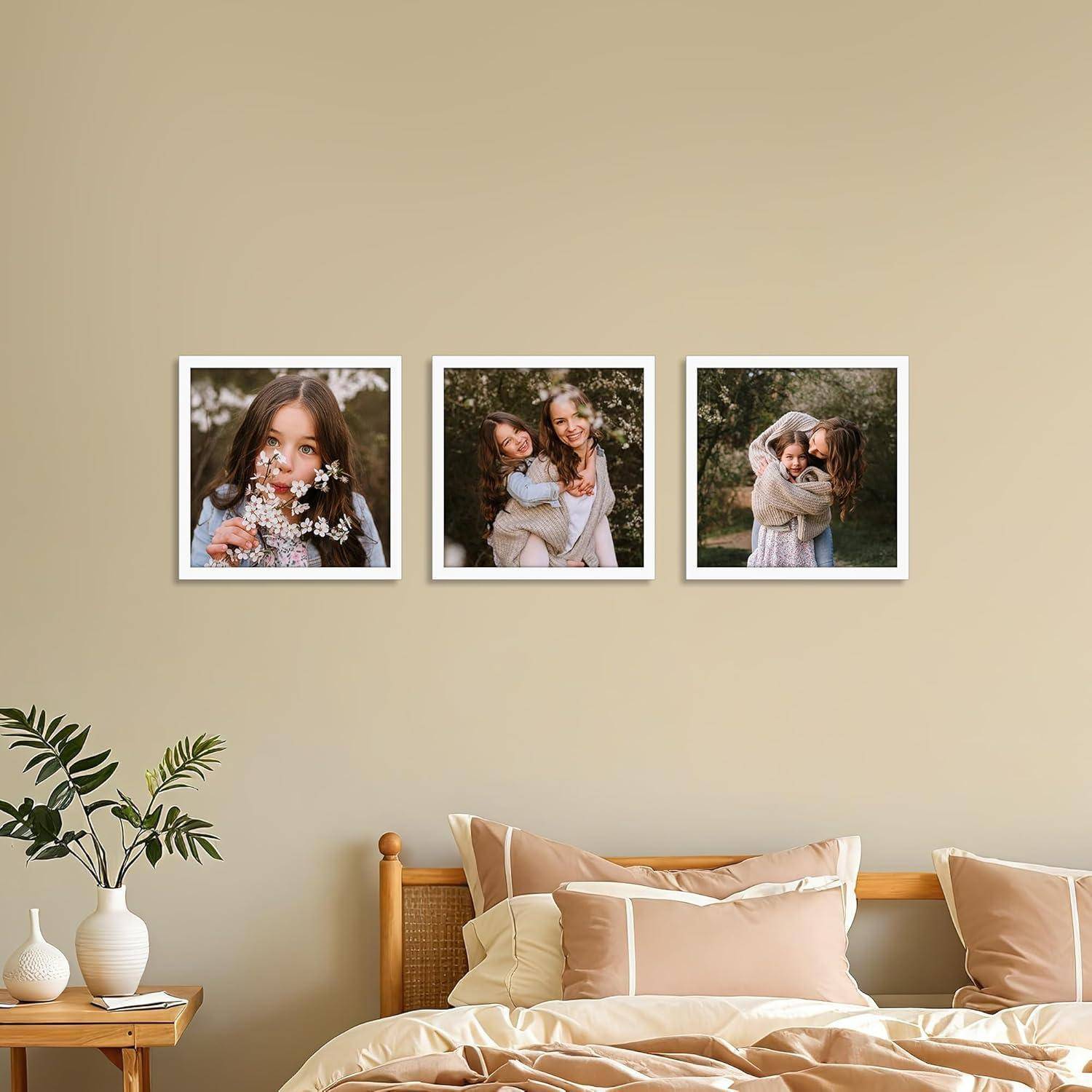 Ein Schlafzimmer mit einem Bett, zwei Vasen auf einem Nachttisch und drei gerahmten Fotos von Personen an einer hellen Wand.