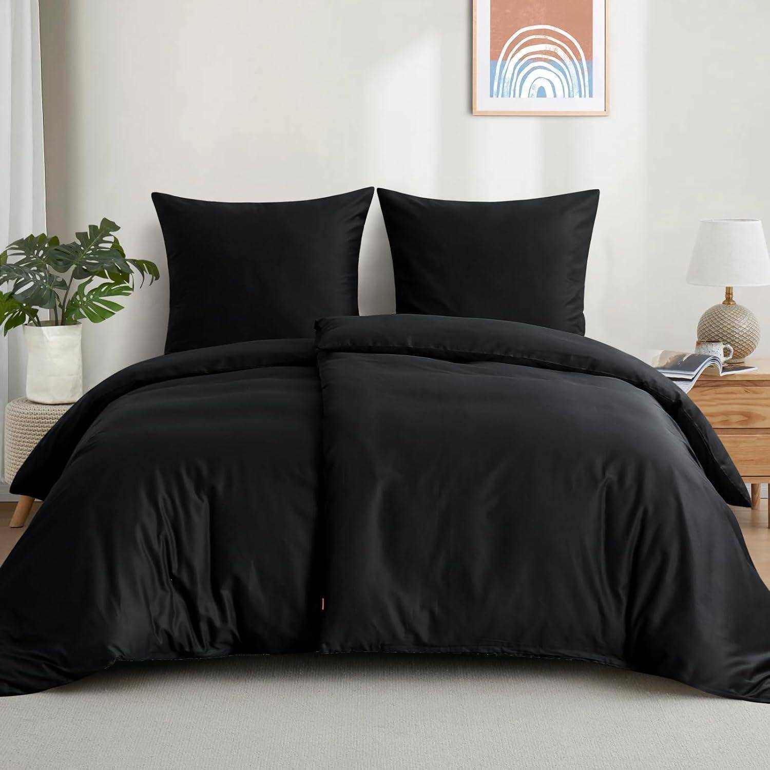 Ein sauber gemachtes Bett mit schwarzen Kissen und Decke, ein Holznachttisch, eine Lampe, eine Pflanze und abstrakte Wandkunst in einem hellen Raum.