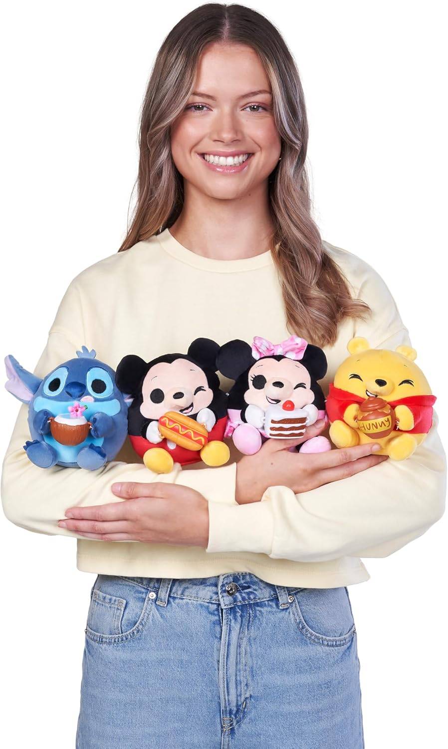 Eine Person hält vier Plüschtiere, die Zeichentrickfiguren ähneln, wobei jedes eine Lebensmittelzutat trägt: einen Cupcake, einen Hotdog, einen Kuchen und einen Honigtopf.