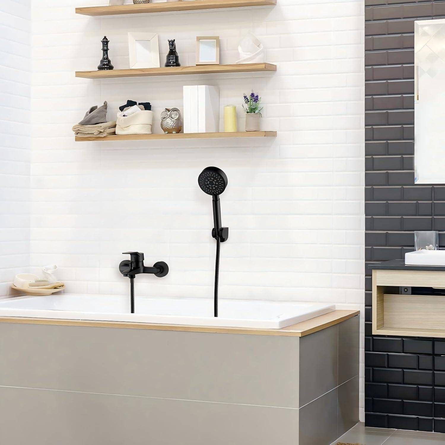 Modernes Badezimmer mit einer grauen Badewanne, schwarzen Armaturen, schwebenden Regalen mit Dekorationen und einem Spiegel über einem Waschbecken an einer schwarzen gefliesten Wand.