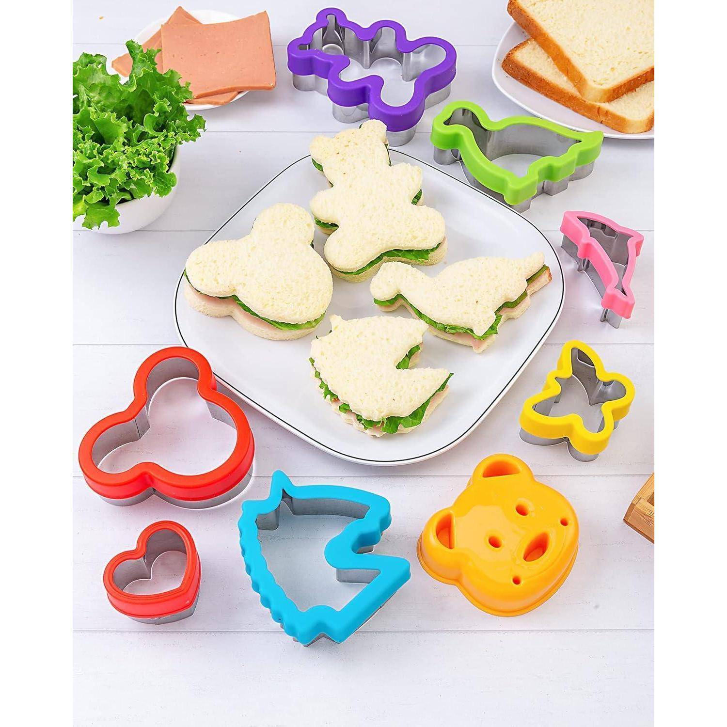 Verschiedene Sandwich-Ausstecher in Formen wie Herz, Dinosaurier und Bär, die Sandwiches in ähnlich verspielten Formen auf einem Teller umgeben.