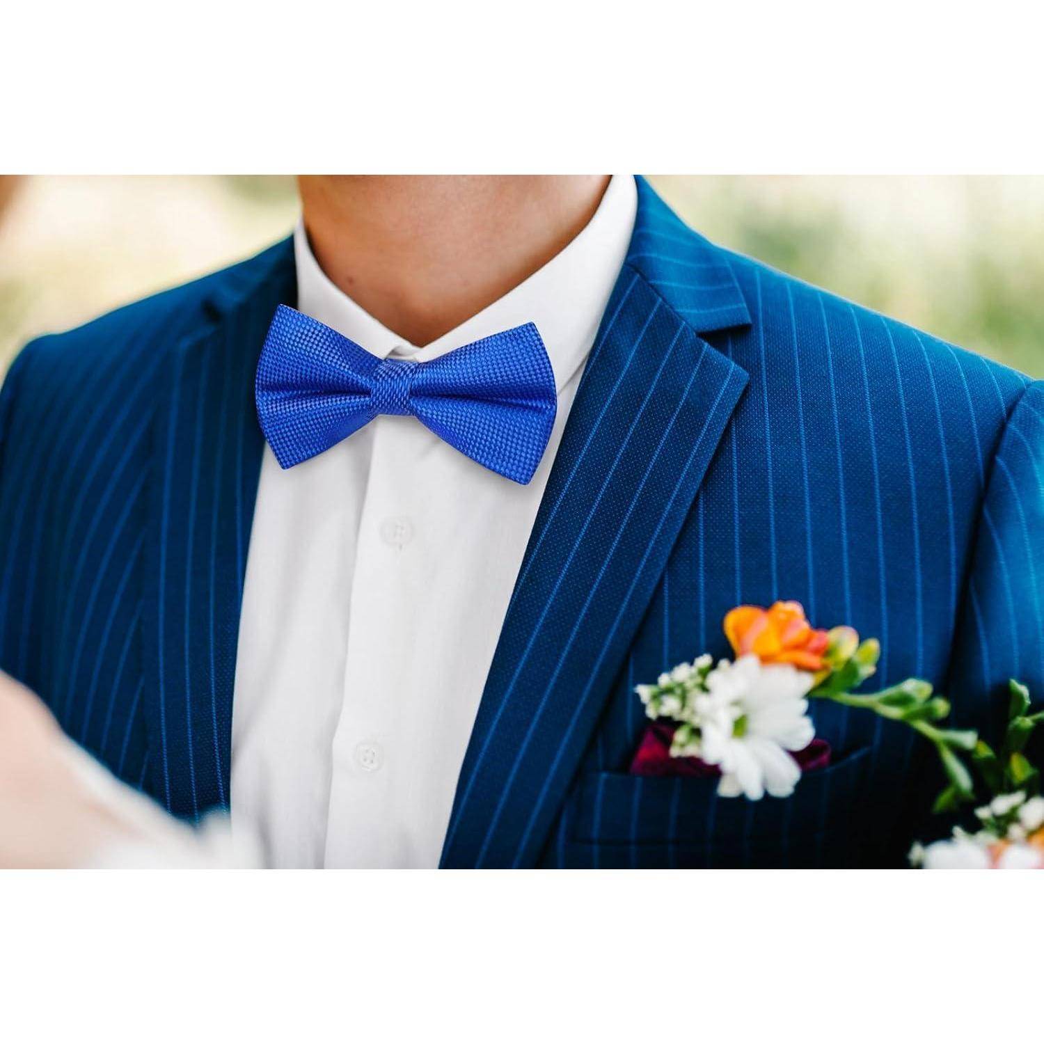 Eine Person in einem blauen Nadelstreifenanzug mit einer blauen Fliege, die ein weißes Hemd trägt. Eine Blumenanstecknadel mit orangefarbenen und weißen Blumen ist sichtbar.