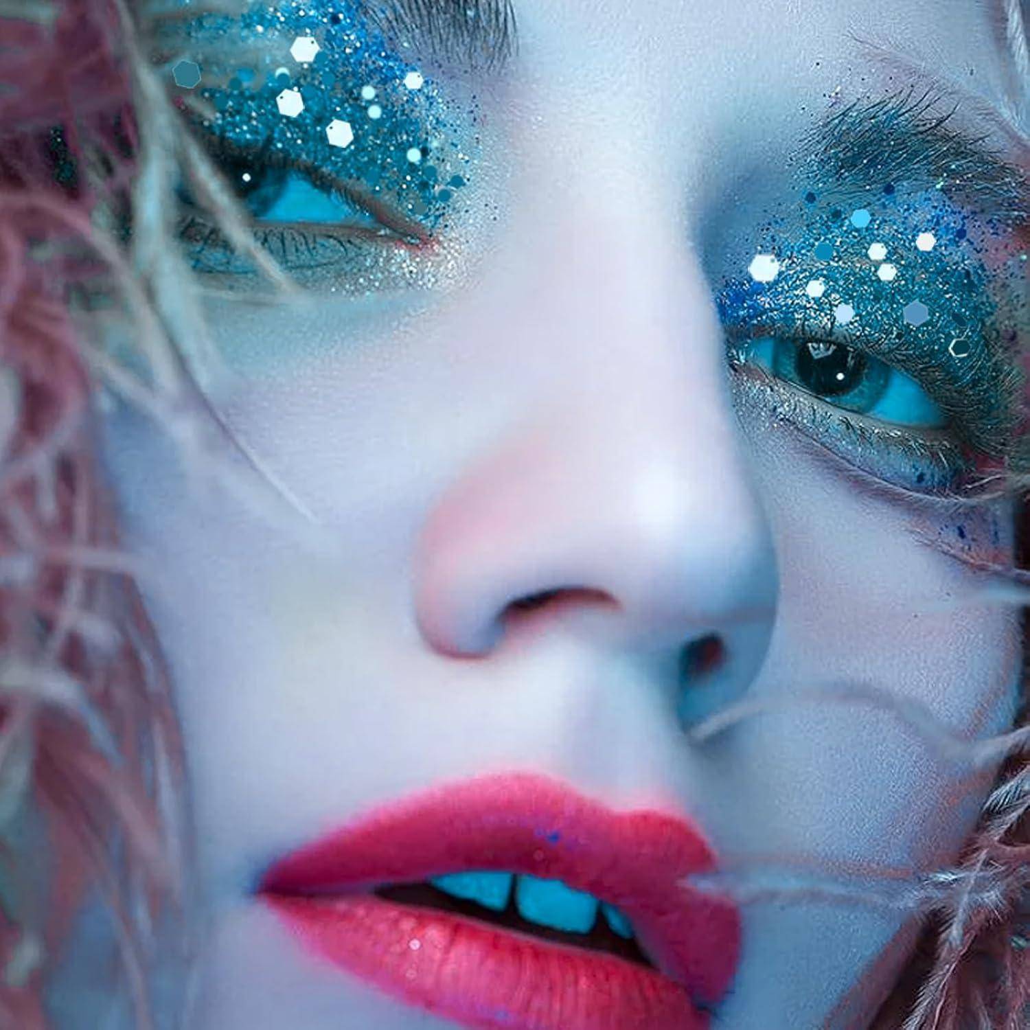 Nahaufnahme eines Gesichts mit leuchtend blauem, glitzerndem Augen-Make-up und knallig pinkfarbenen Lippen, das ein auffallendes und künstlerisches Make-up präsentiert.