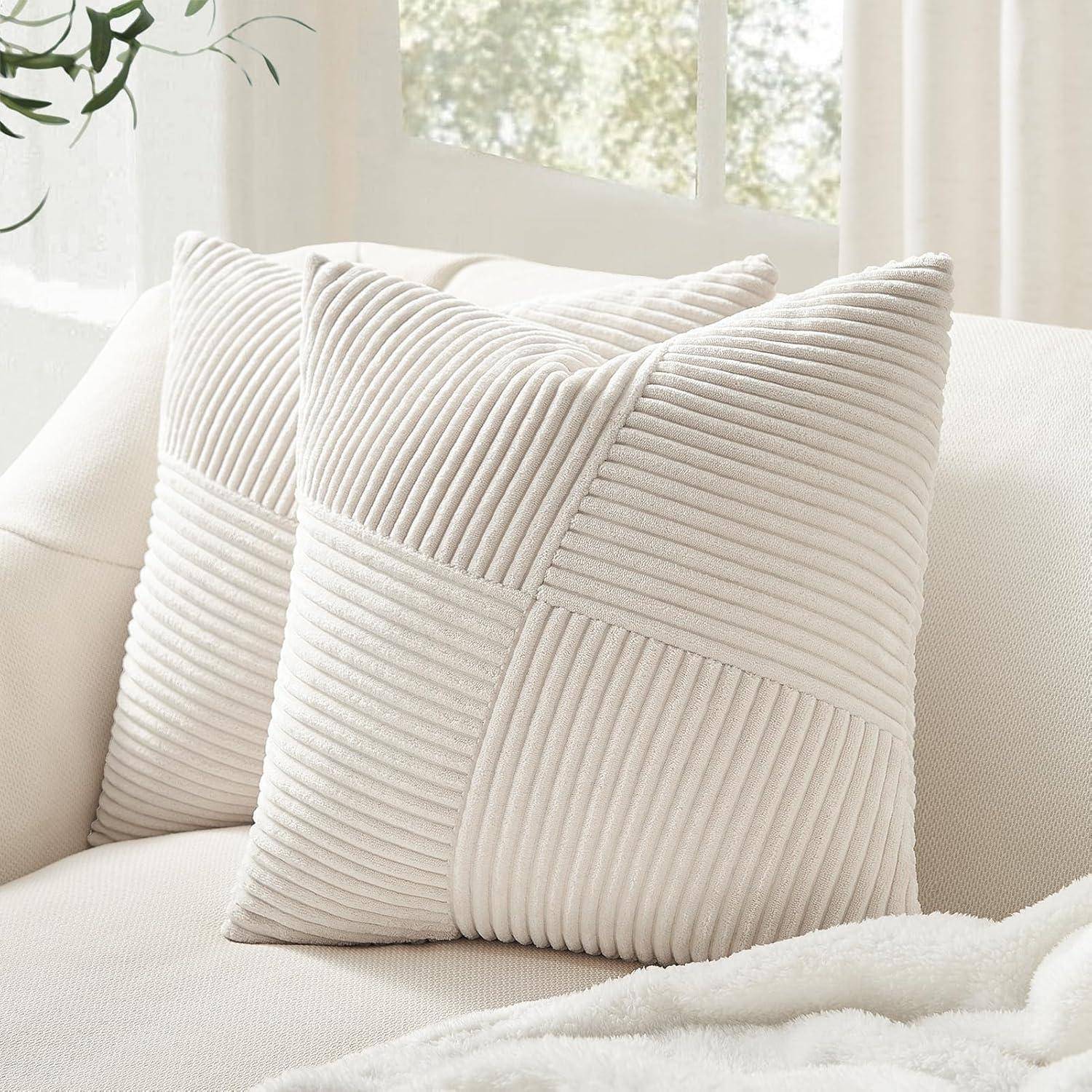 Zwei strukturierte beige Kissen auf einem weißen Sofa in der Nähe eines Fensters, die eine gemütliche, friedvolle Atmosphäre im Wohnraum schaffen.