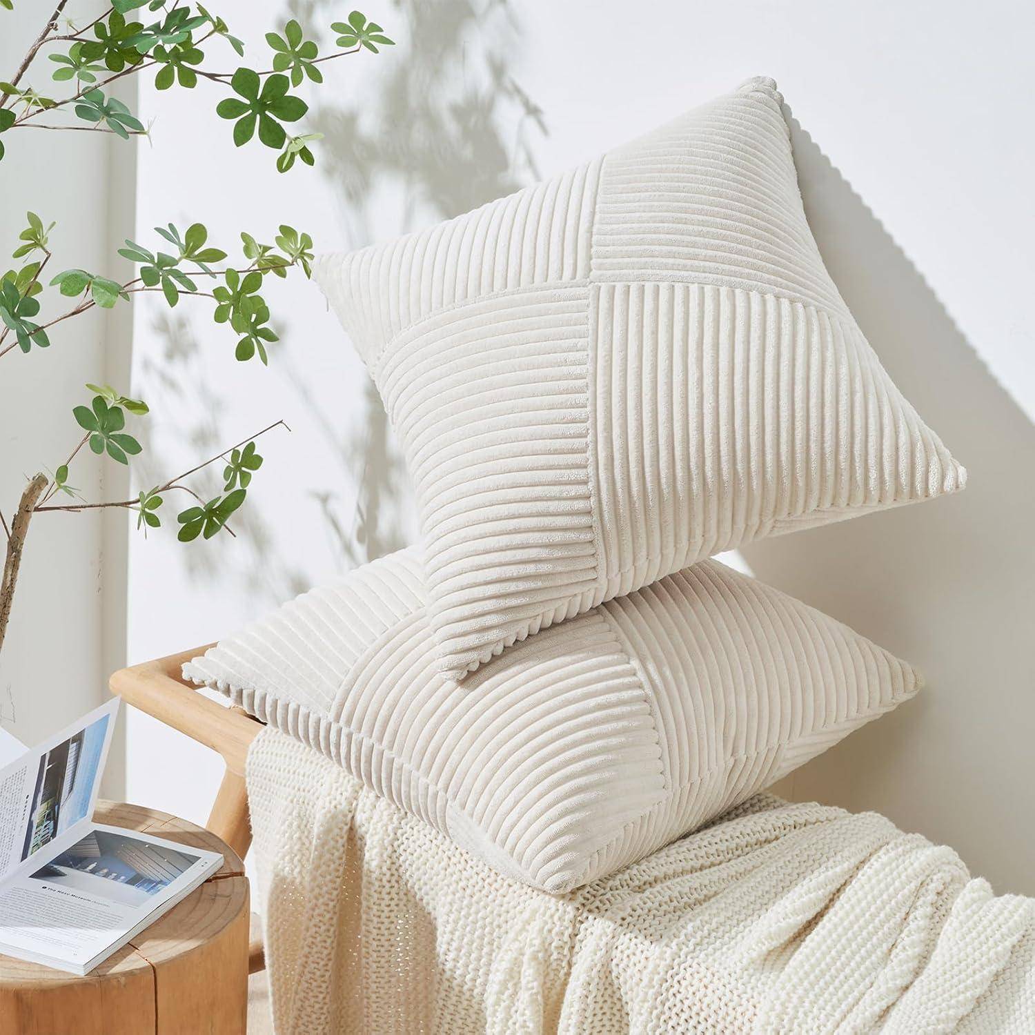 Zwei beige Kissen mit gerippter Textur auf einer beigen Strickdecke, neben einem Couchtisch mit einem Buch und einer Topfpflanze.