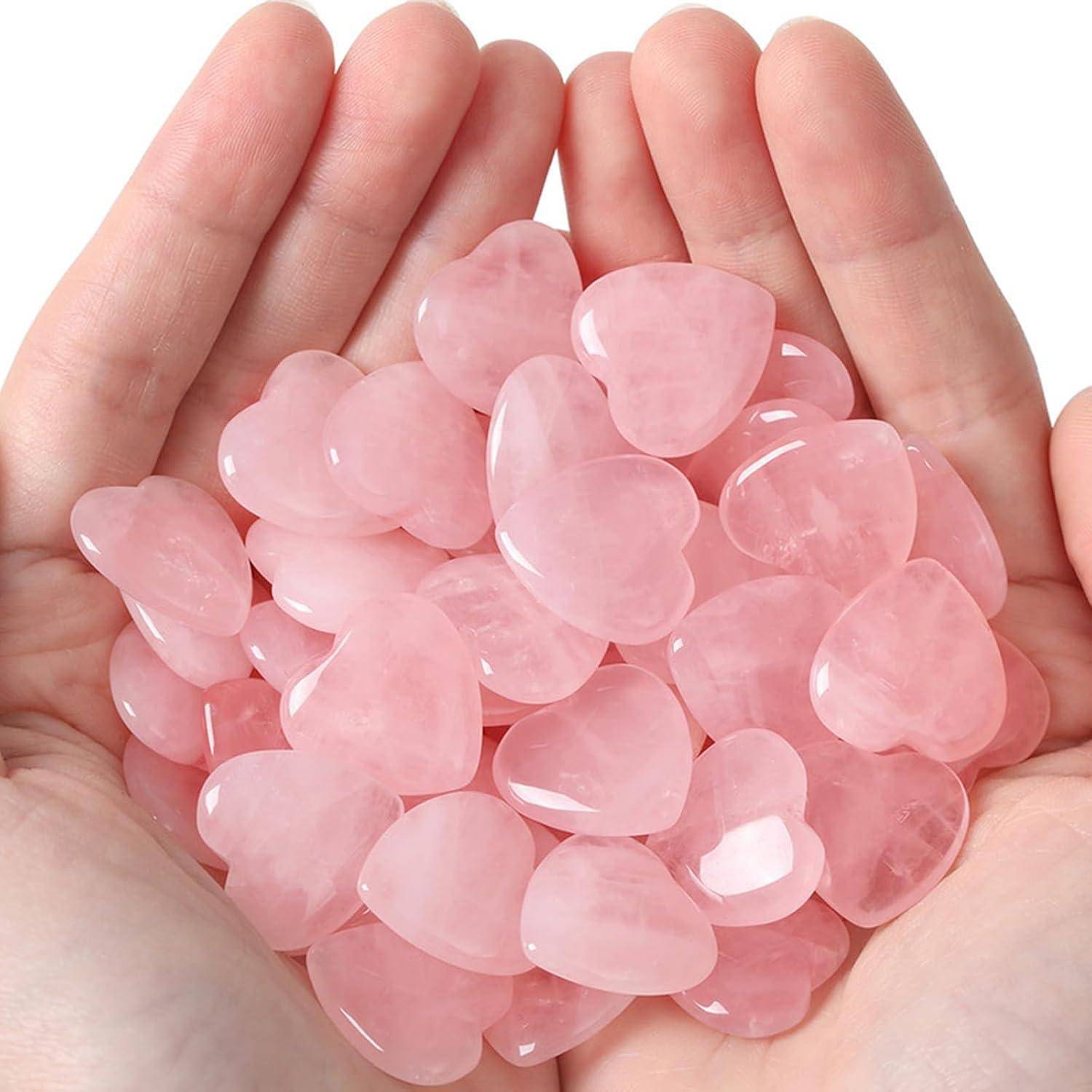 Hände, die einen Stapel polierter, herzförmiger Steine in Rosa halten.
