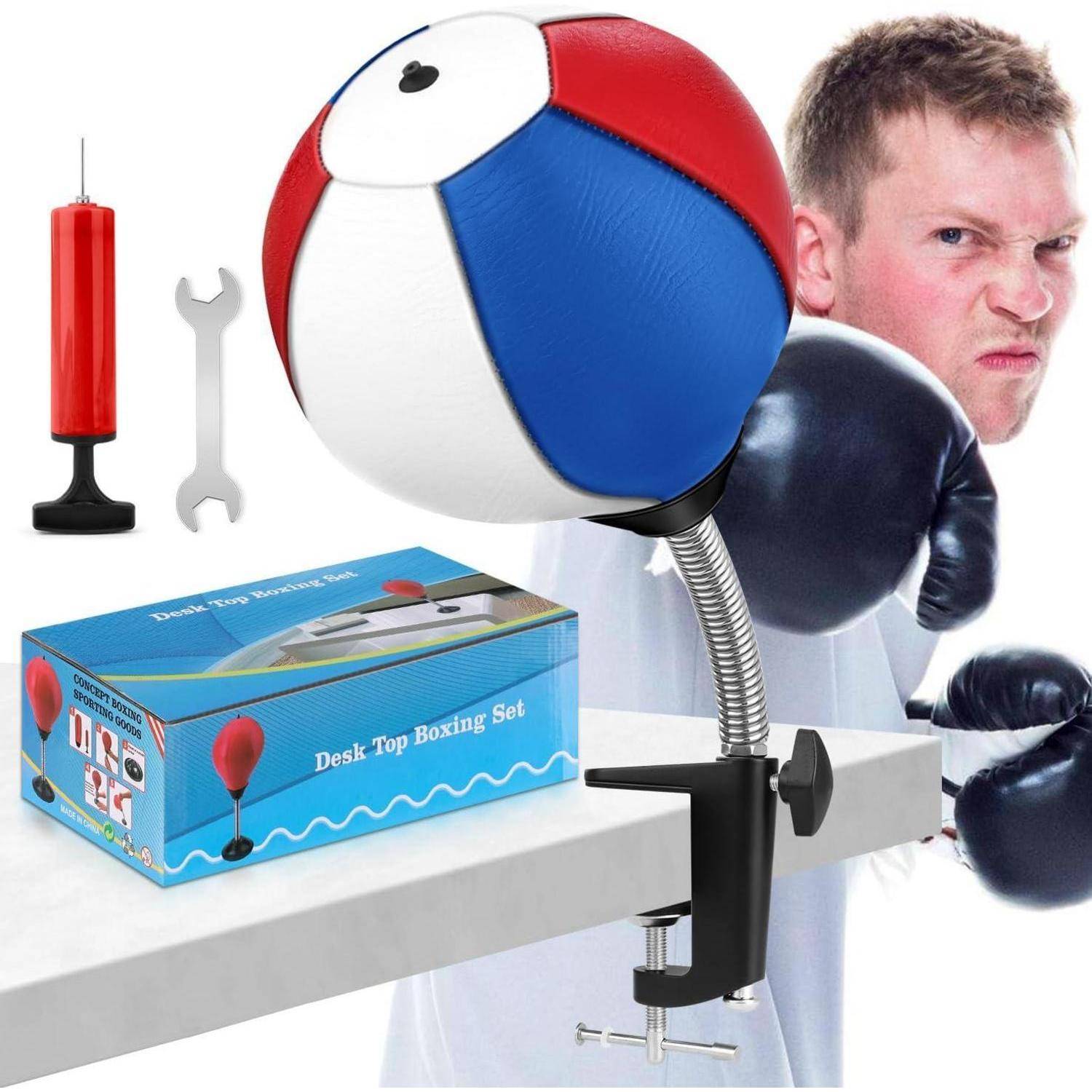 Eine Person mit Boxhandschuhen steht einem Schreibtisch gegenüber, auf dem eine Tischklemm-Punchingball-Anlage installiert ist, zusammen mit einer kleinen Pumpe, einem Schraubenschlüssel und einer Verpackungsbox.
