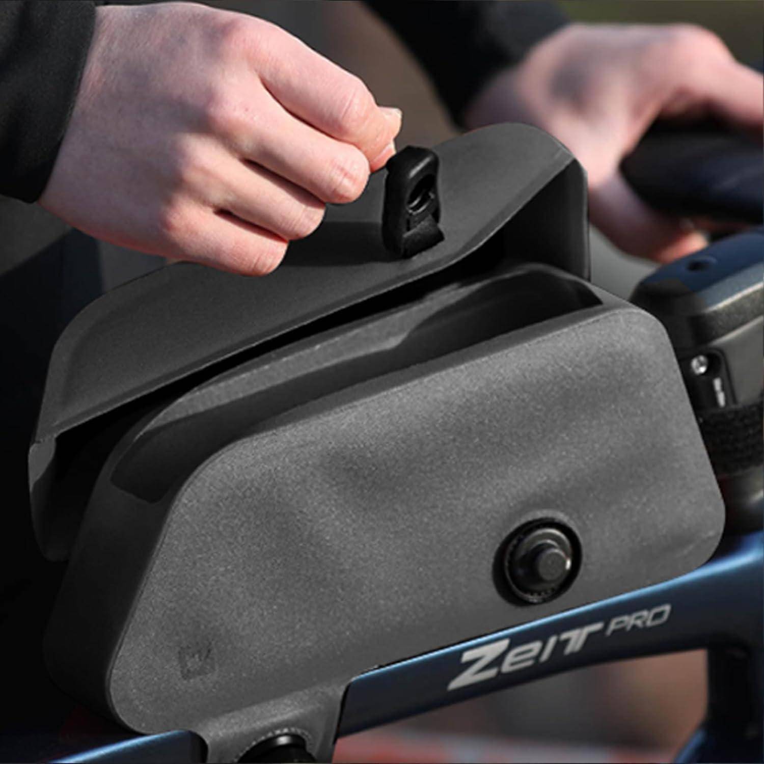Eine Hand öffnet ein schwarzes Staufach an einem Fahrrad namens 'Zeit Pro', was auf Zugriffsmöglichkeiten auf Stauraum während des Radfahrens hindeutet.