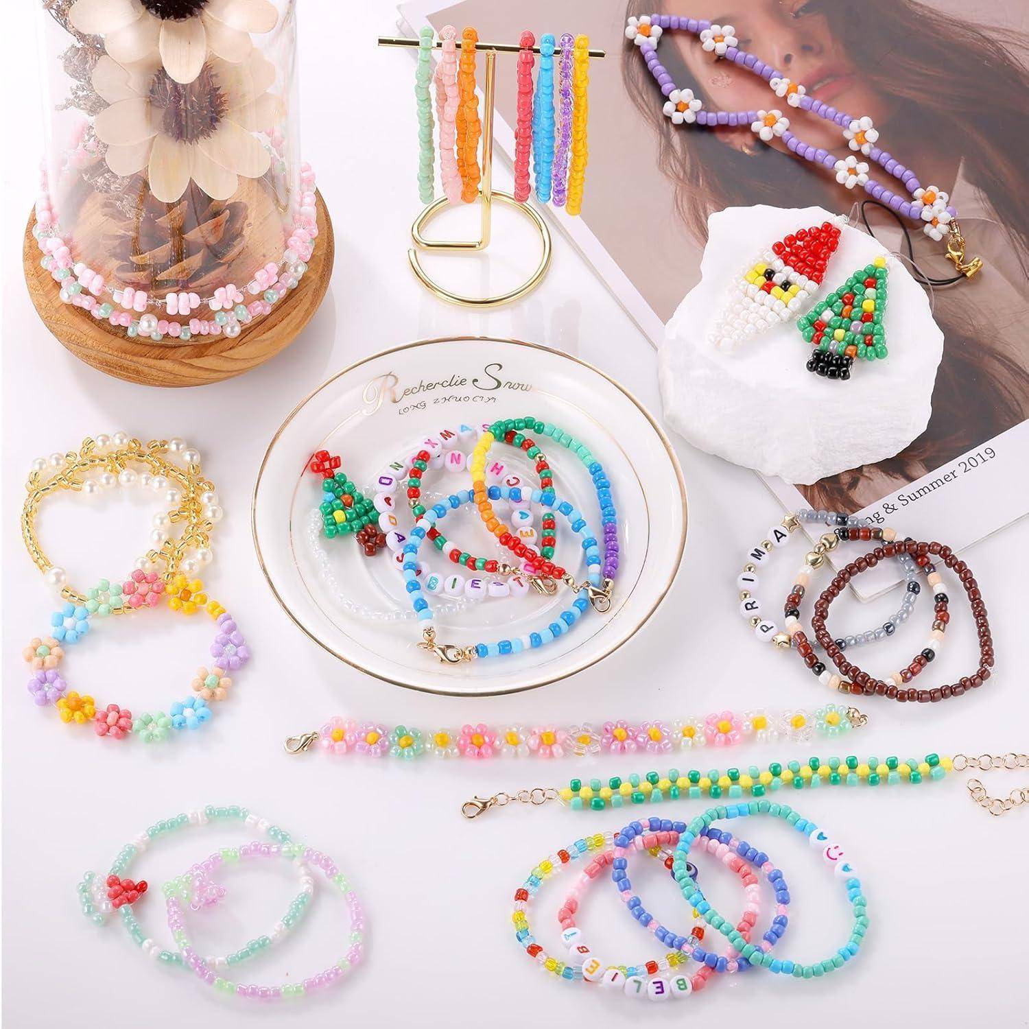 Eine Sammlung bunter Perlenschmuck wird auf einer weißen Oberfläche präsentiert, darunter Armbänder, Halsketten und eine herzförmige Brosche.