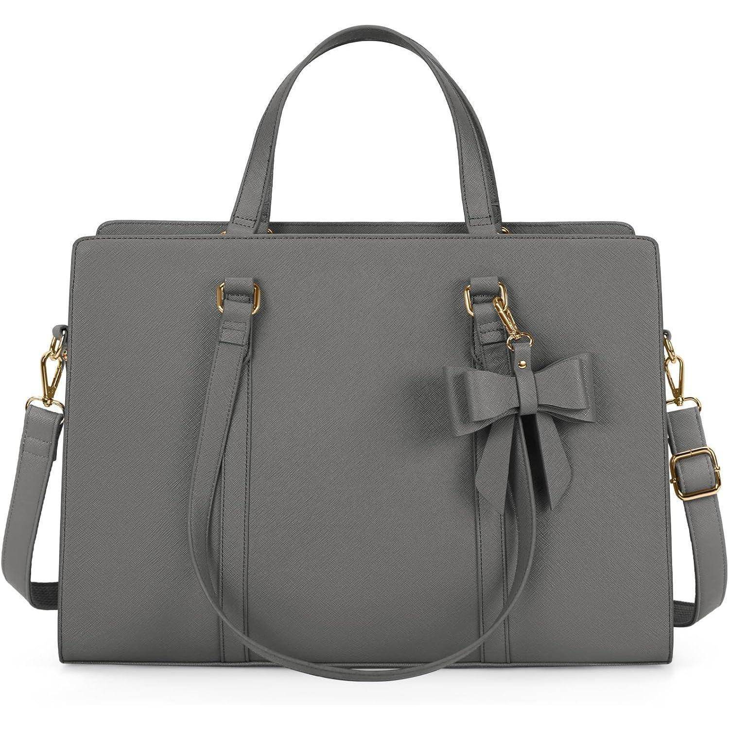 Eine graue Handtasche mit zwei Henkeln und einem abnehmbaren Schulterriemen. Eine dekorative Schleife ist an einem Henkel mit goldenen Beschlägen befestigt.