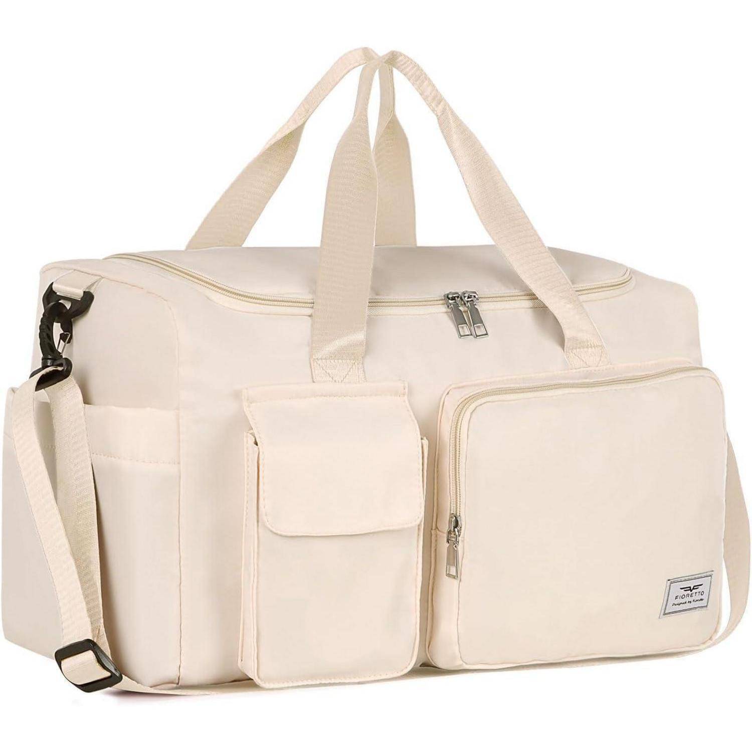 Ein cremefarbener Reisetasche mit Doppelgriffen, abnehmbarem Schultergurt und mehreren Taschen, darunter ein großes Fach mit Reißverschluss an der Vorderseite.