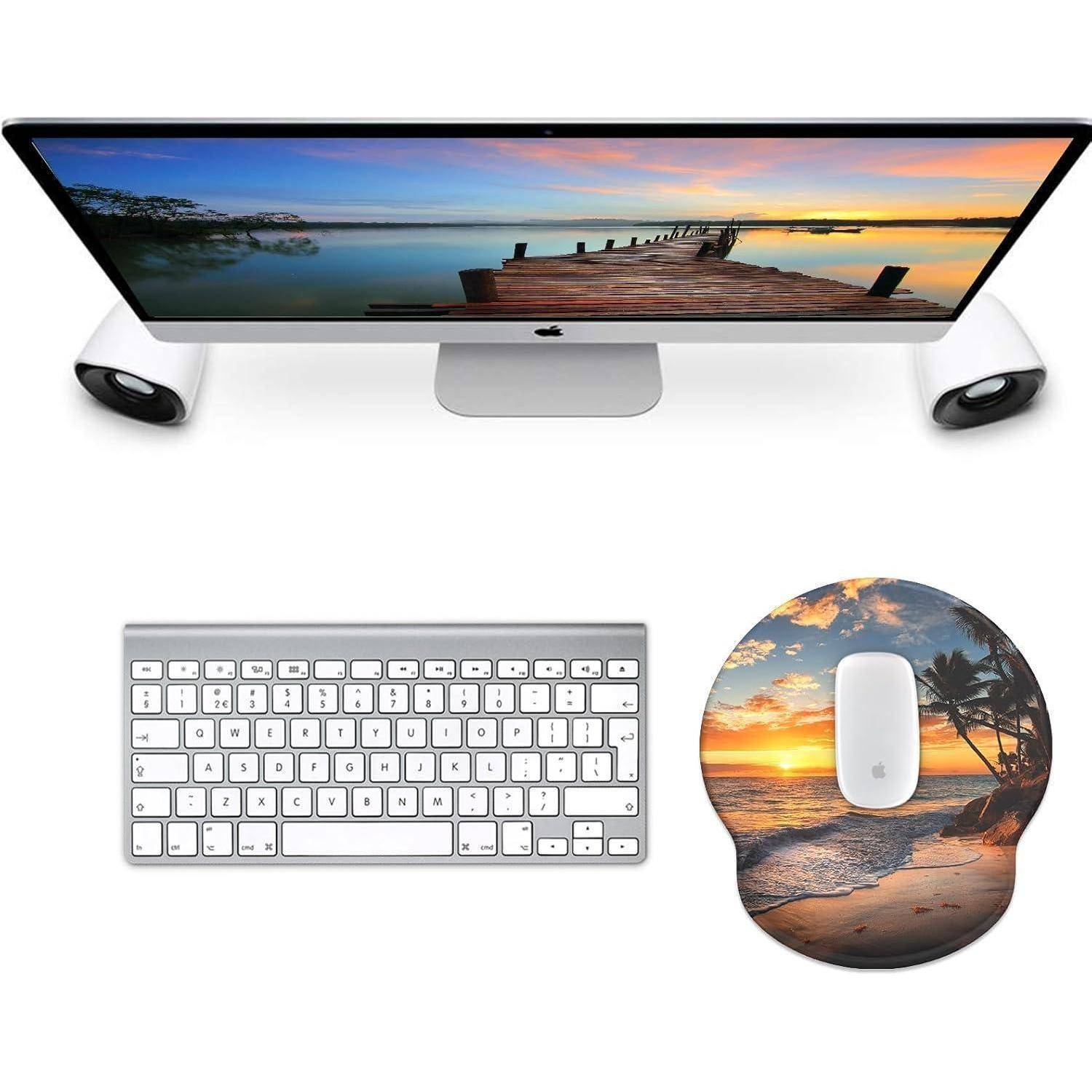 Ein Desktop-Computer, der einen Dock auf einem von Sonnenuntergang beleuchteten See zeigt, mit einer Tastatur und einer Maus auf einem Mousepad, das eine Strand-Sonnenuntergangsszene darstellt.