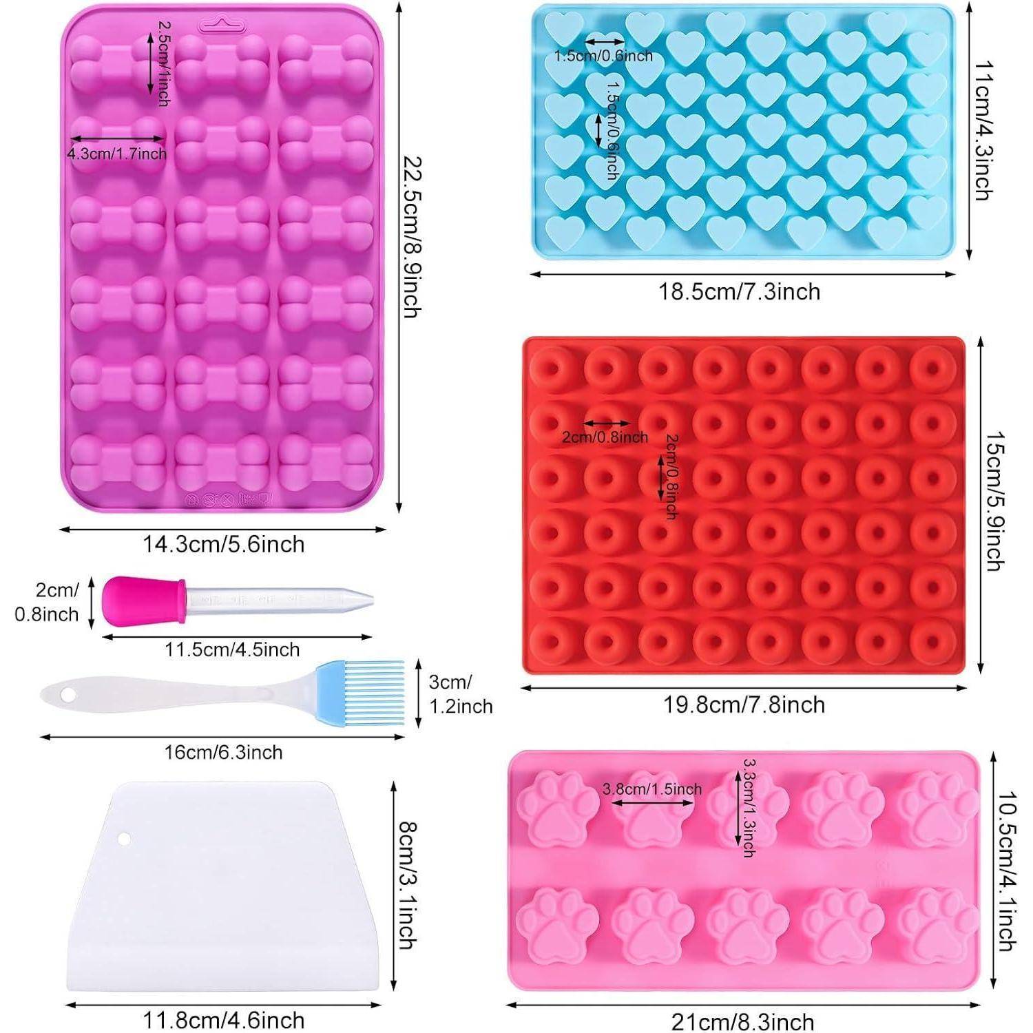 „Set aus Silikonbackformen in verschiedenen Formen und Farben mit Abmessungen: lila Blumen, blaue Herzen, rote runde Formen, rosa Pfotenabdrücke; inklusive Teigschaber und Werkzeug.