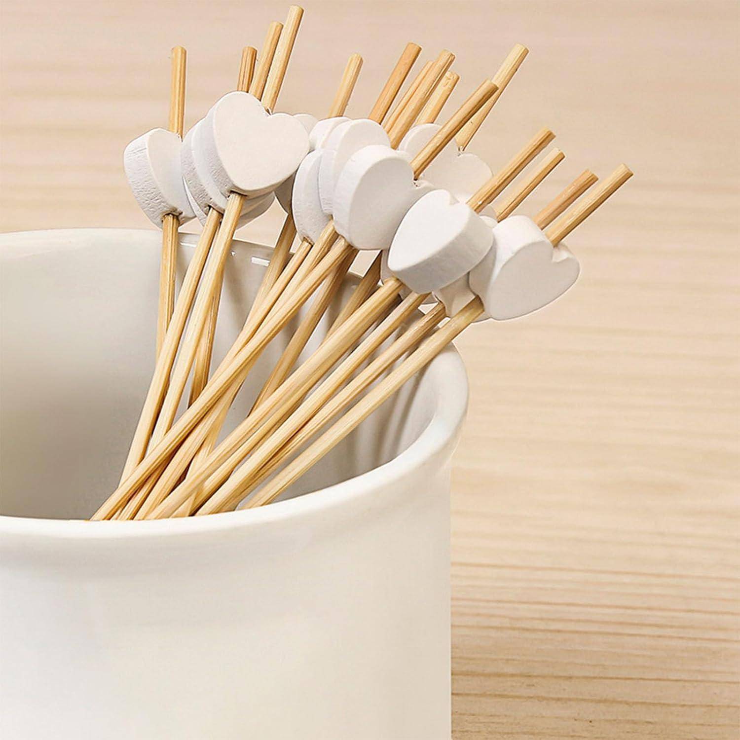 Stöcke mit weißen herzförmigen Köpfen in einer weißen Tasse auf einer Holzoberfläche.