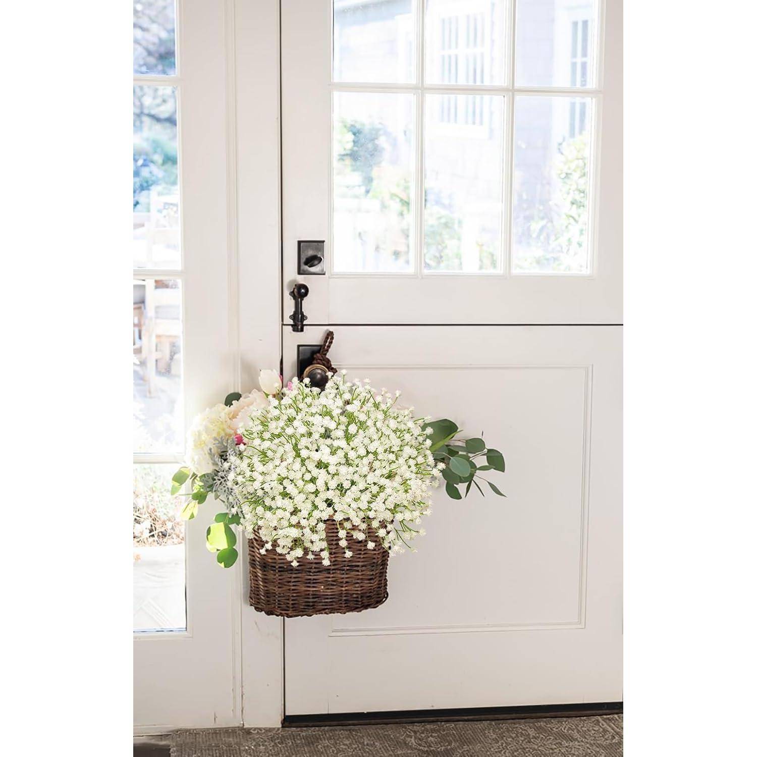 Ein Flechtkorb, gefüllt mit weißen Blumen, hängt an einer weißen Tür, während Sonnenlicht durch das Glas strömt und eine helle und einladende Atmosphäre schafft.