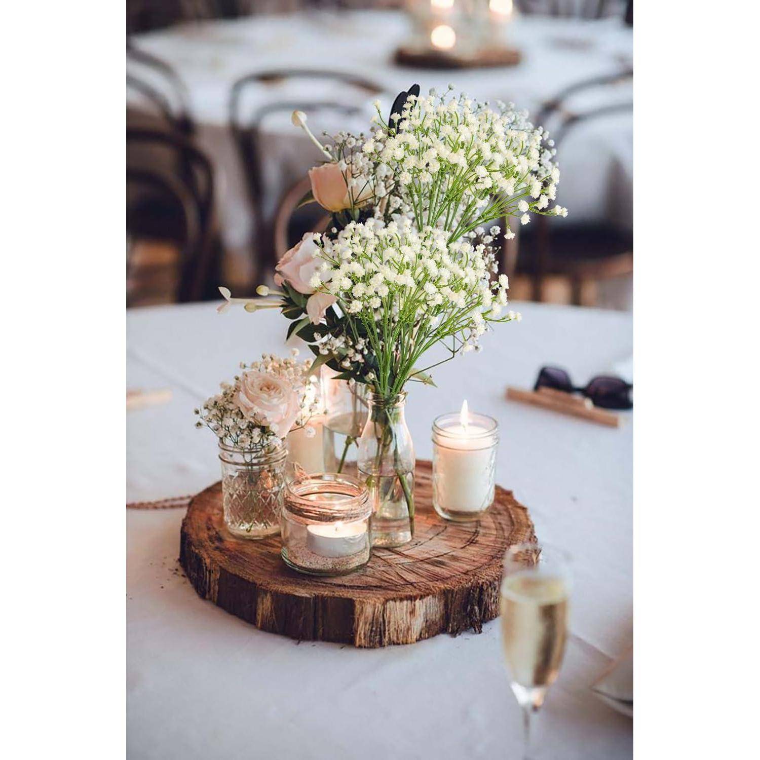 Ein Mittelstück mit weißen Blumen und Kerzen auf einem Holzbrett schmückt einen Tisch bei einer Veranstaltung und verleiht dem Ambiente einen rustikalen und eleganten Touch.