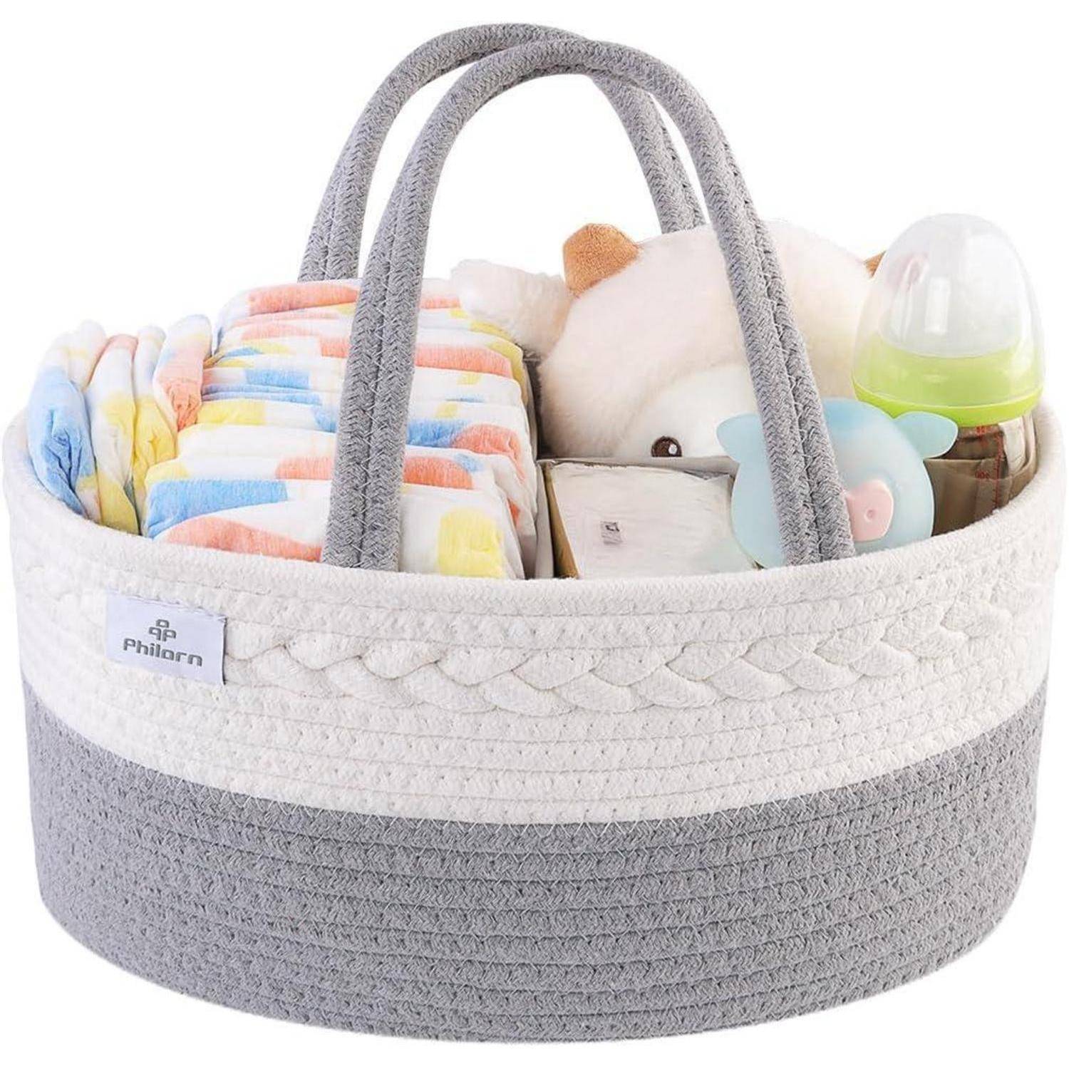 Ein geflochtener Korb enthält sorgfältig angeordnete bunte Windeln, eine Babyflasche, ein weiches Spielzeug und einen Schnuller und deutet damit auf ein Babyversorgungsthema hin.