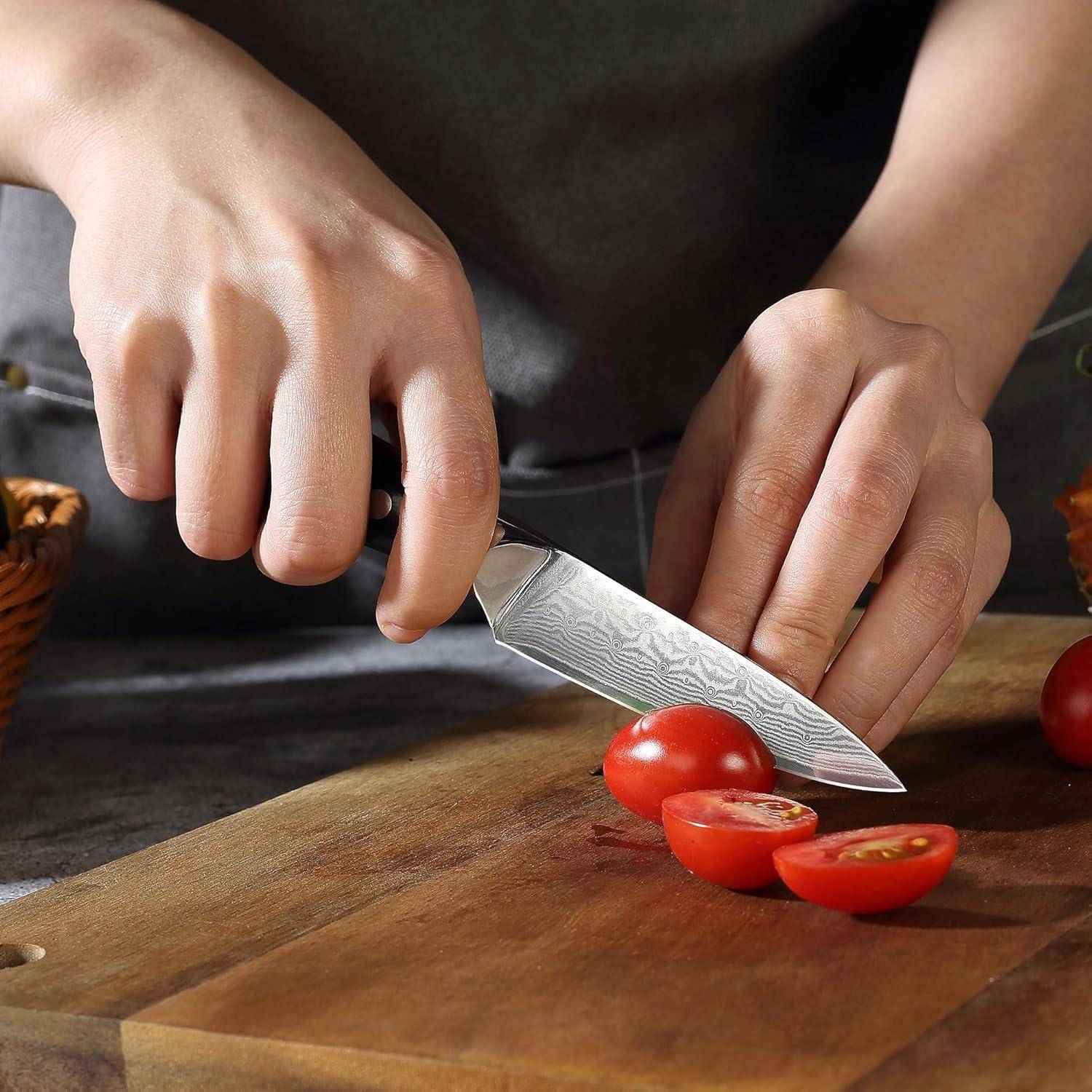 Eine Person schneidet Tomaten auf einem Holzschneidebrett mit einem Kochmeser.