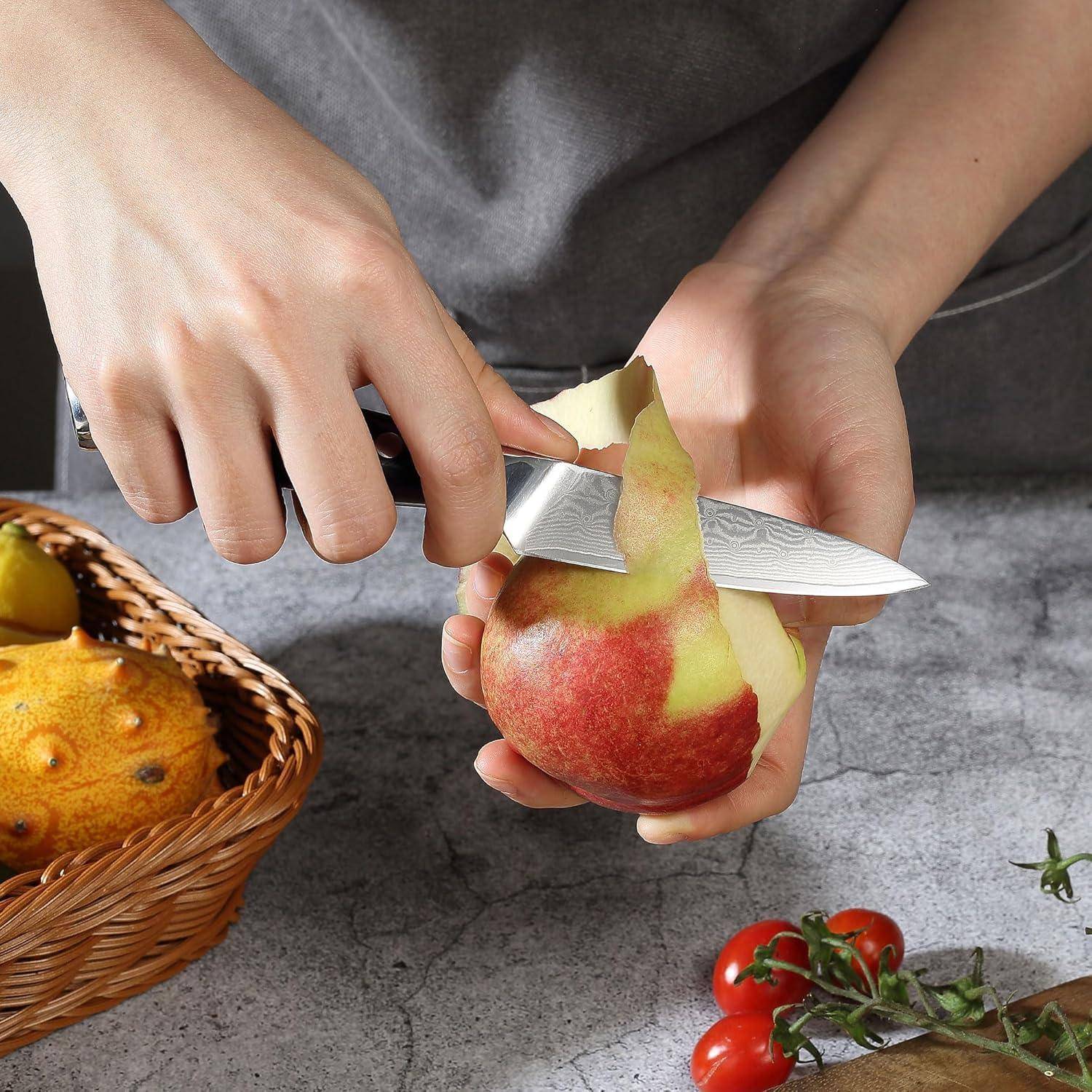 Eine Person, die einen Apfel mit einem Messer über einer Arbeitsplatte schält, neben einem Flechtkorb mit Obst und einigen Tomaten an der Seite.