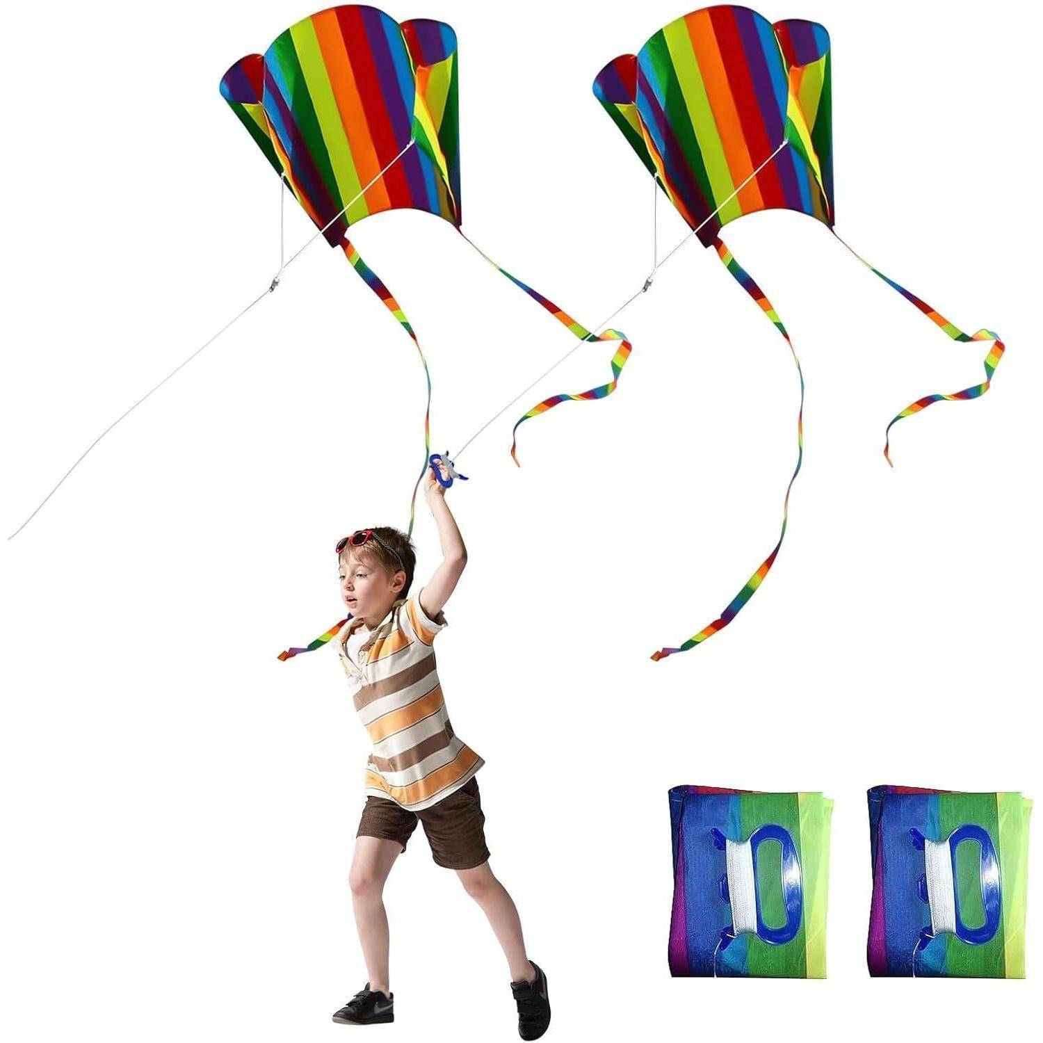 Ein Kind mit gestreiftem Shirt fliegt zwei bunte Regenbögen-Drachen, die jeweils lange, wehende Schwänze haben, vor einem weißen Hintergrund.