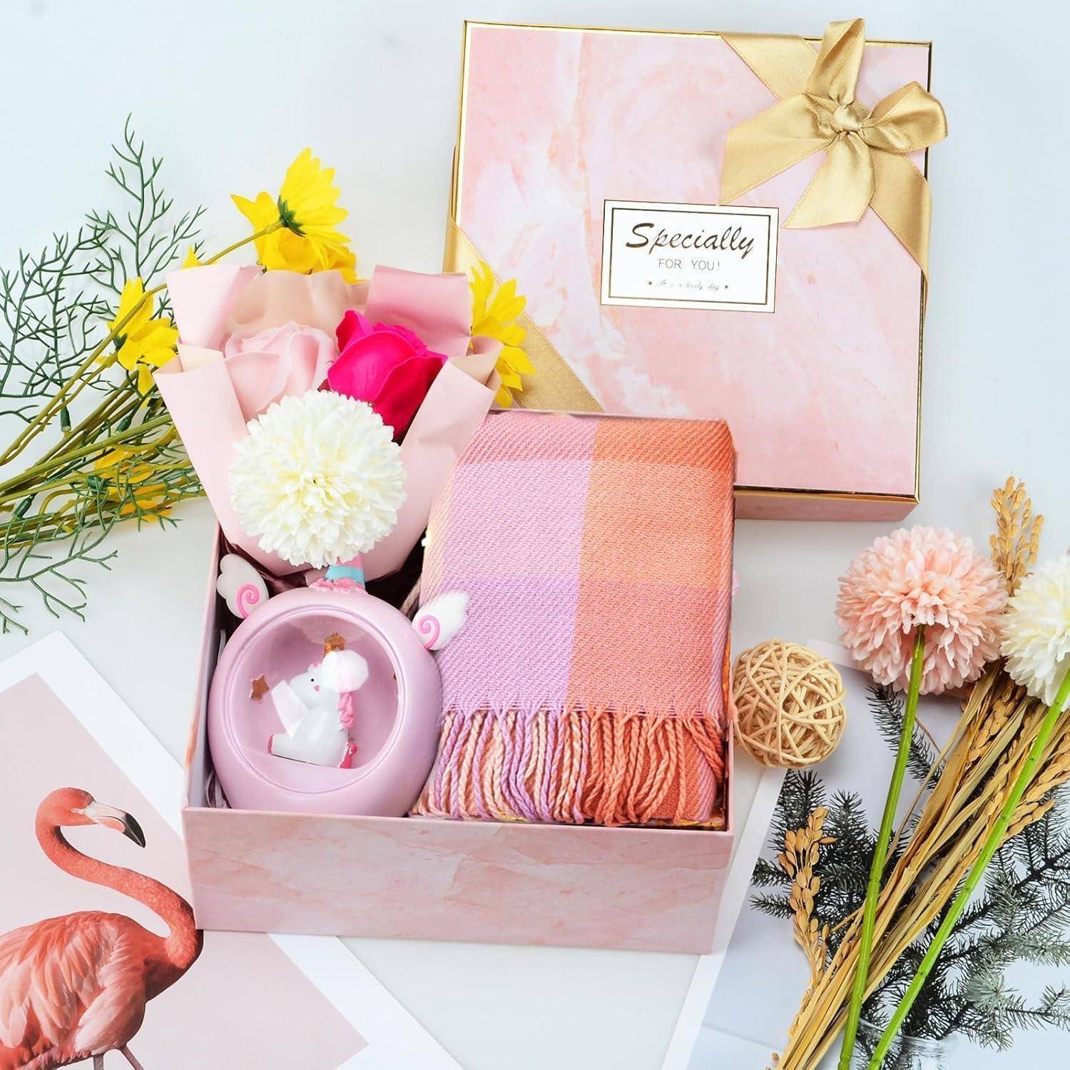 Geschenkbox mit rosa Schal, Einhorn-Tasse, Blumen und einer Karte mit der Aufschrift ‚Speziell für dich', dekoriert mit einem Band. Flamingo-Aufdruck daneben.