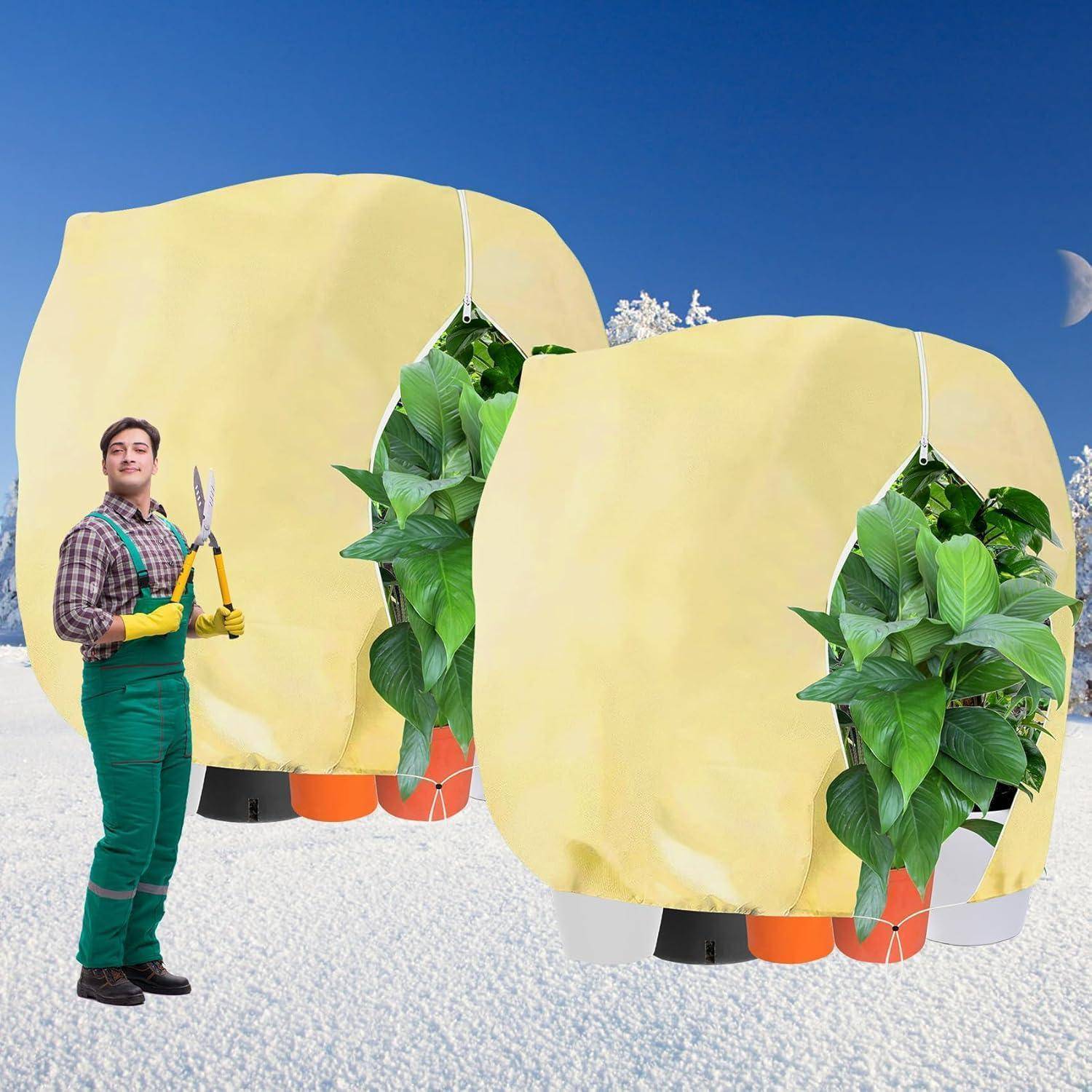 Eine Person in grüner Arbeitskleidung hält eine Gartenschere im Freien in einer verschneiten Umgebung und steht neben zwei großen, abgedeckten Pflanzen.