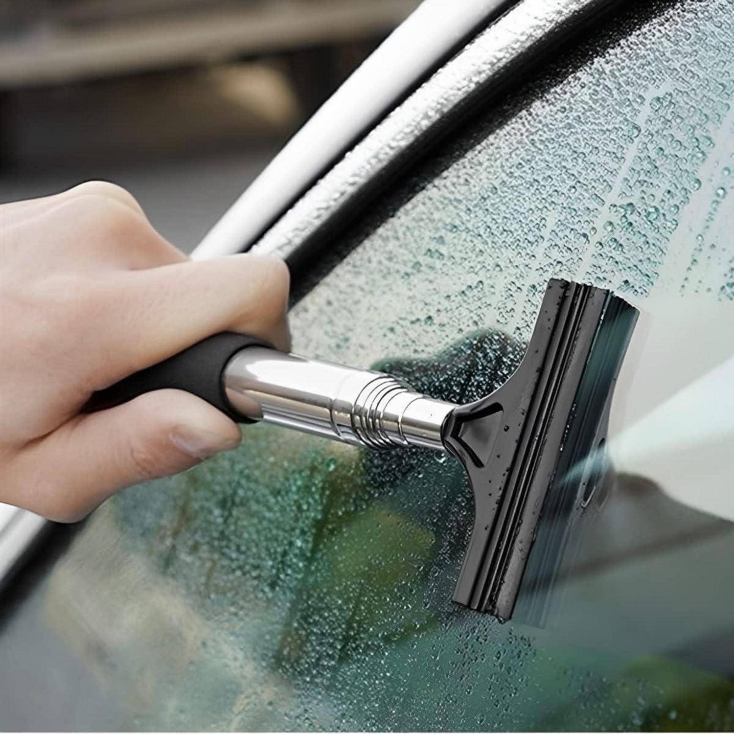 Eine Hand benutzt einen Abzieher, um eine nasse Autoscheibe zu reinigen und Wassertropfen zu entfernen, um eine klare Sicht zu gewährleisten. Der Griff ist schwarz und ergonomisch gestaltet.