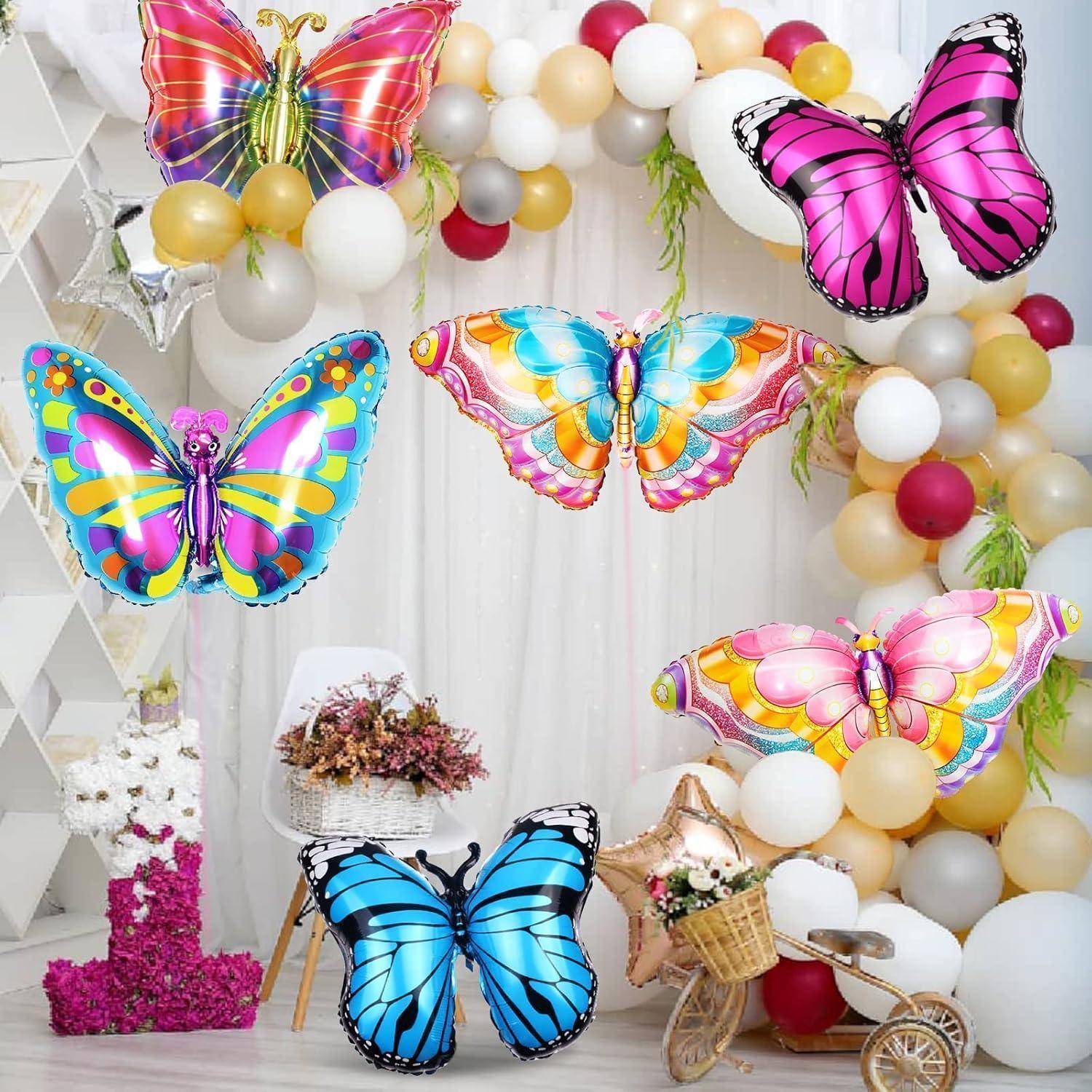 Bunte Schmetterlinge vor einer Kulisse von Luftballons und Blumen. Ein großer Luftballonbogen in Gold-, Weiß- und Burgunderfarbtönen rahmt die Szene ein.