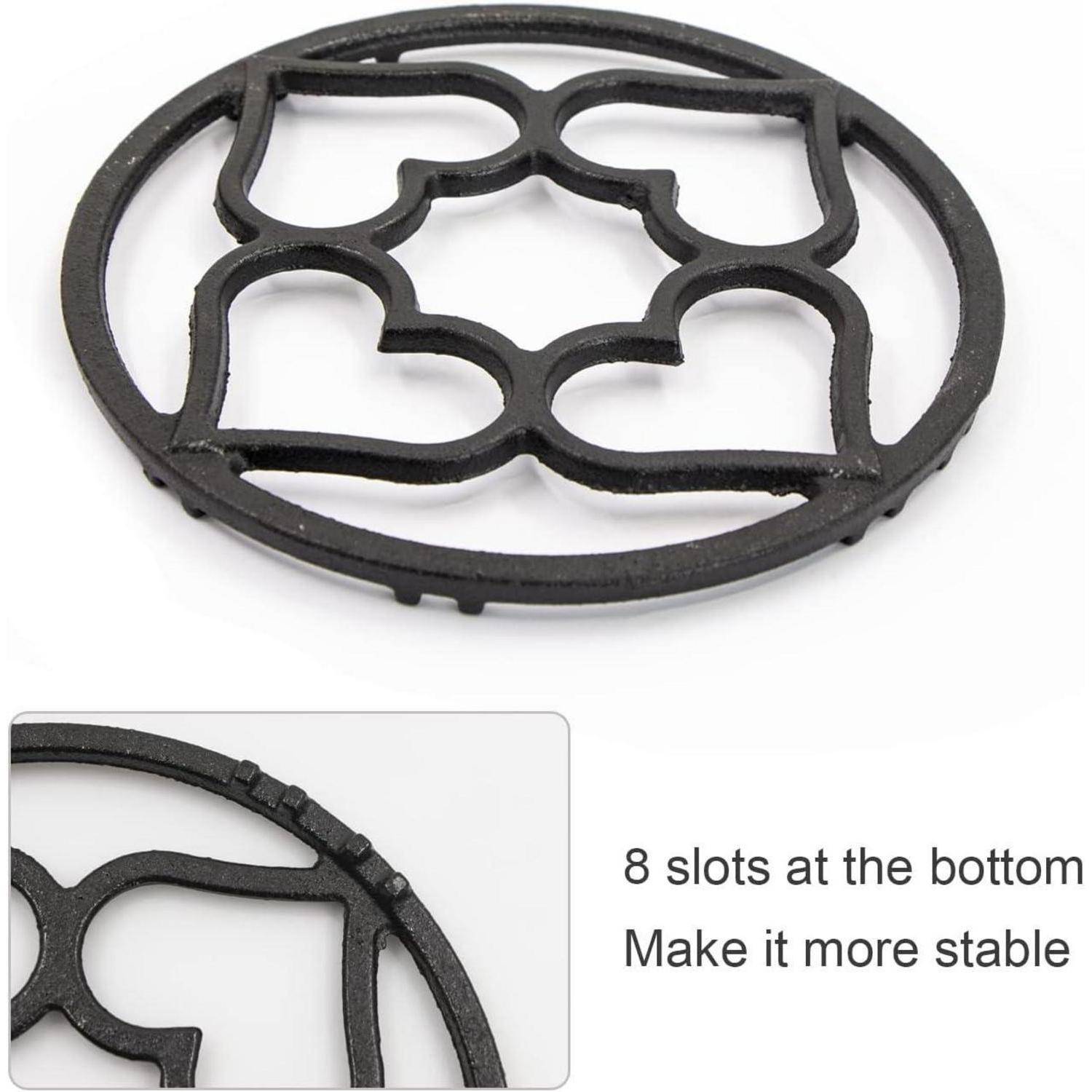 Ein runder schwarzer Metalluntersetzer mit einem dekorativen Design und acht Aussparungen am Boden für Stabilität.