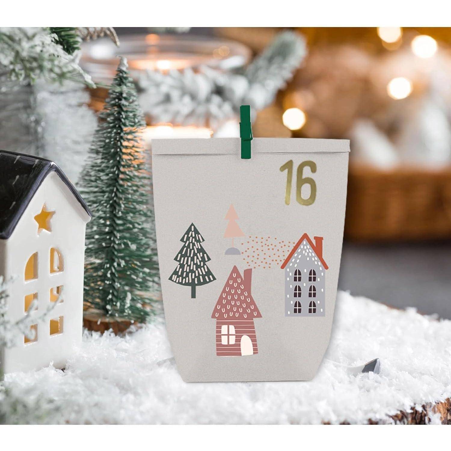 Eine festliche Winterszene mit einer dekorativen Papiertüte, die illustrierte Häuser und Bäume zeigt, mit der Nummer '16' markiert, auf einer schneebedeckten Oberfläche.