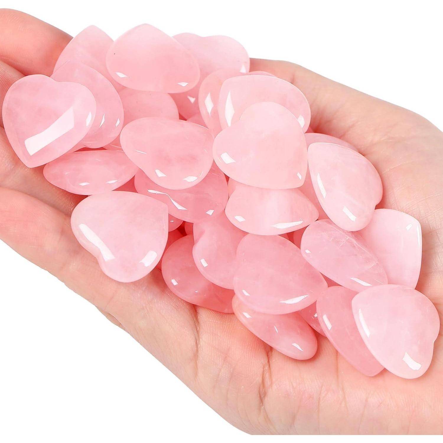 Eine Hand hält einen Stapel kleiner, polierter, herzförmiger Steine in Rosa, die Liebe oder Zuneigung symbolisieren.