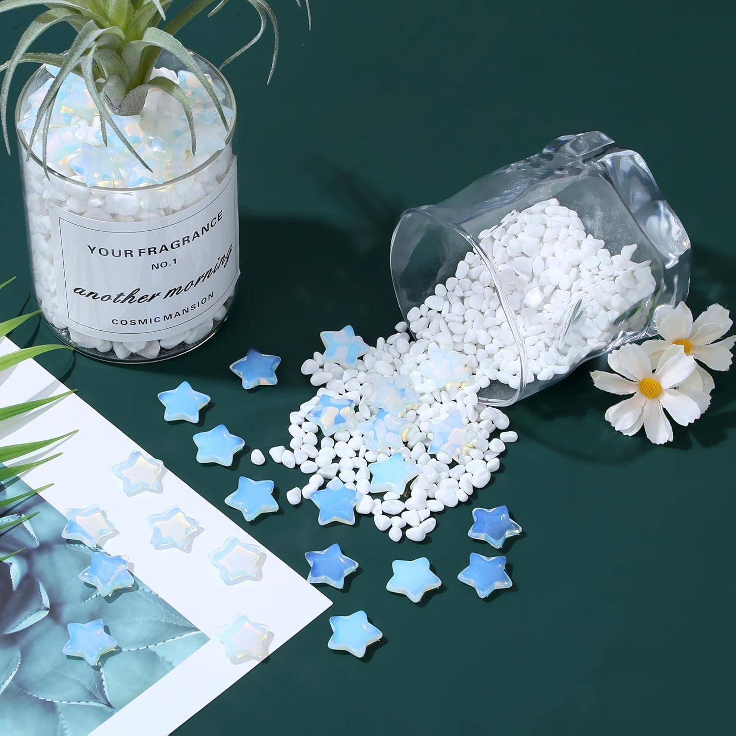 Eine Farn in einem Topf und verstreute weiße Kieselsteine auf einer grünen Oberfläche, mit blauen, sternförmigen Perlen und weißen Blumen in der Nähe.