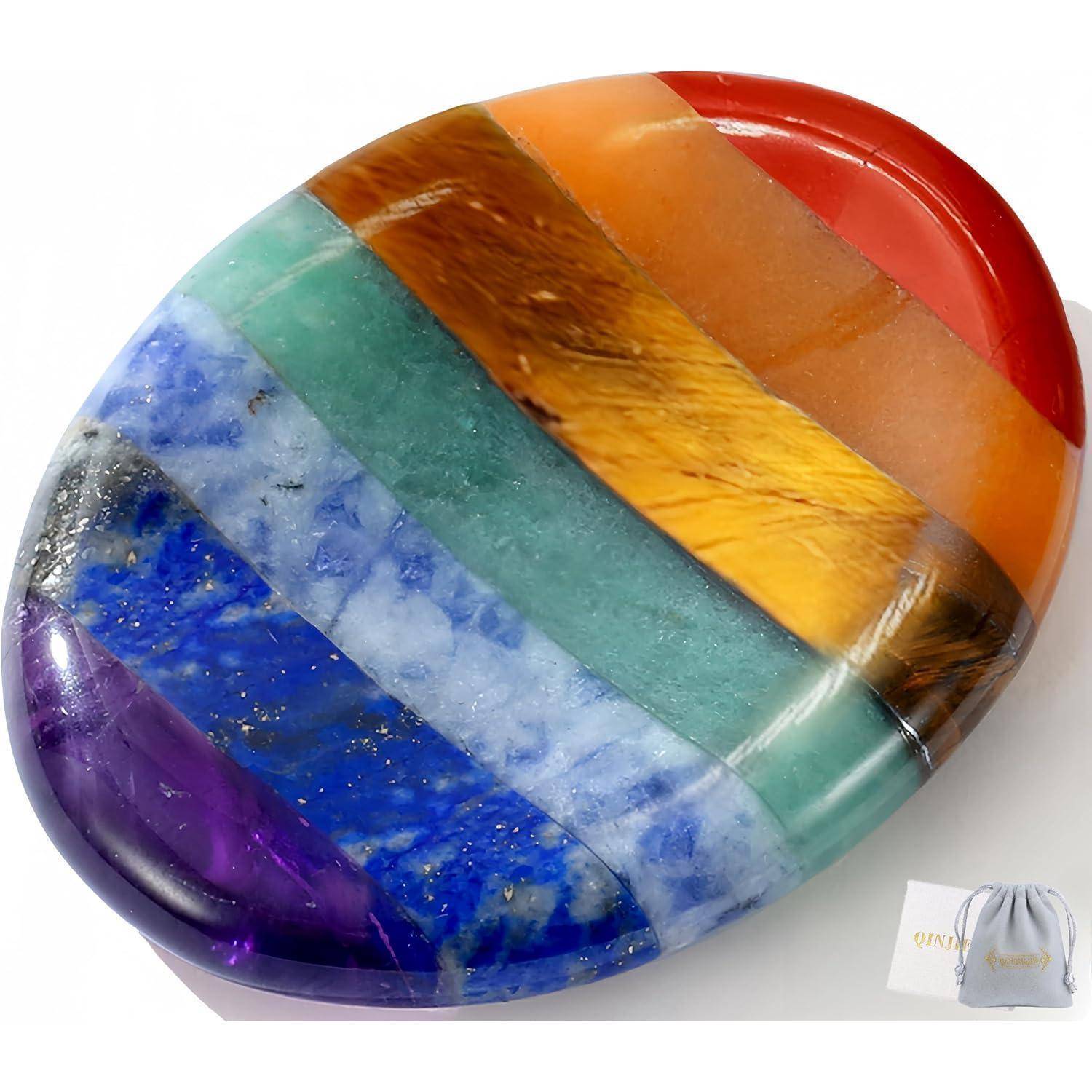 Ein glatter, ovalförmiger Stein, der in lebendige horizontale Bänder von Rot, Orange, Gelb, Grün, Blau und Violett unterteilt ist und Harmonie symbolisiert.